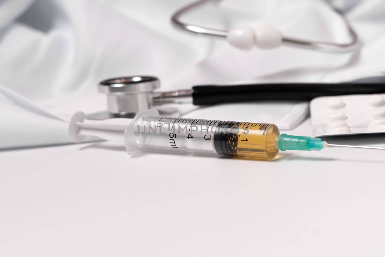 syringe, stethoscope and pills on a white doctor's gown by joseantona