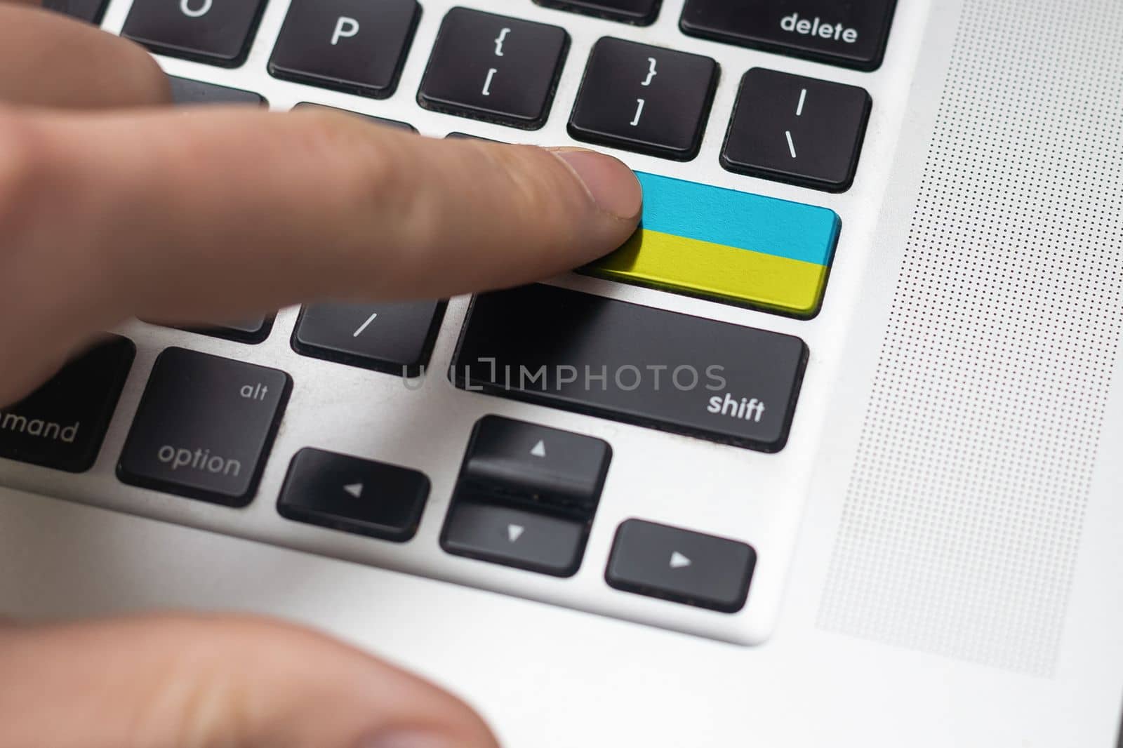 Pressing enter button with Ukraine flag, represents a cyber-attack of Ukraine, metaphor of learning Ukrainian language, black keyboard close up, front view, selective focus