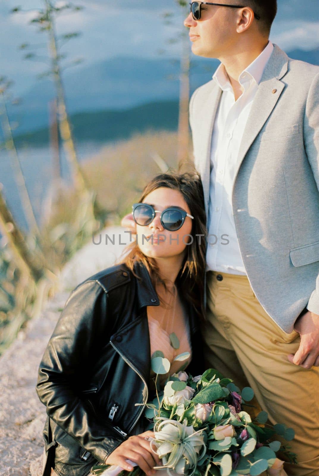 Seated bride leaned against the standing groom. High quality photo