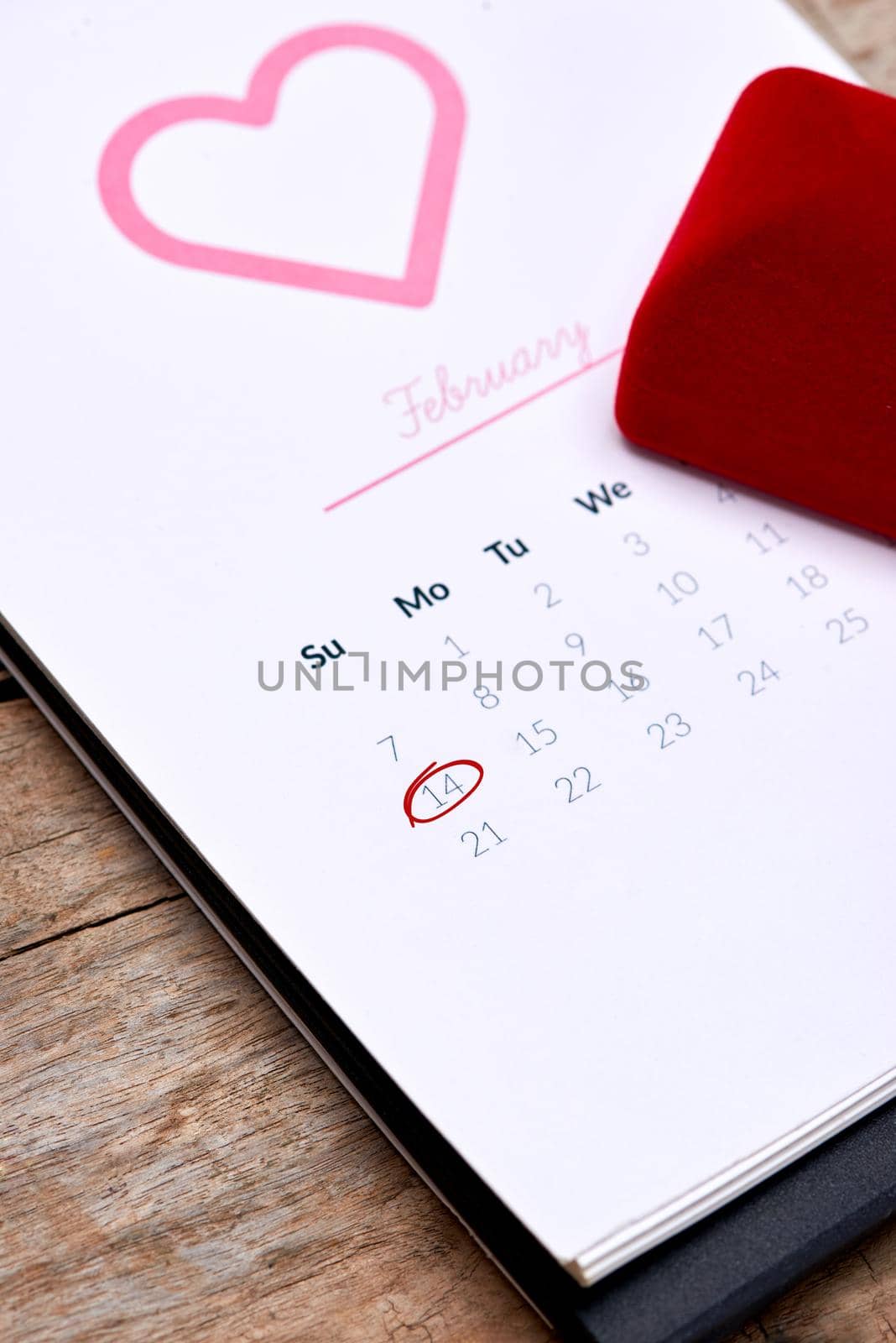 Calendar showing the date 14th of February. Red rose, hearts and gift box on wooden table.