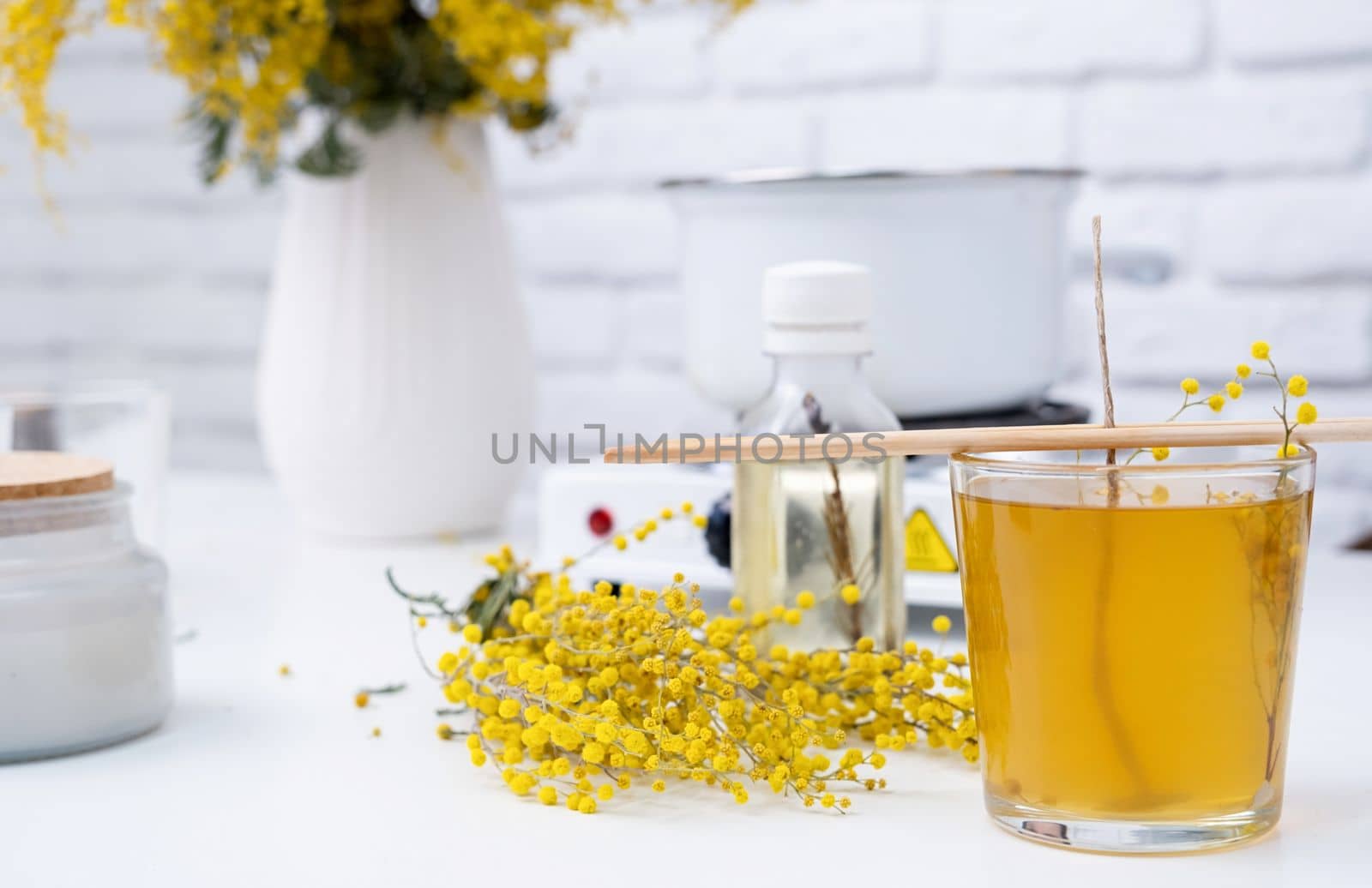 Creative hobby at home. making decorative aroma candle with mimosa flowers at table