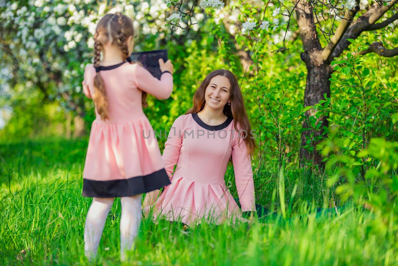 mother and daughter take pictures using a tablet in nature