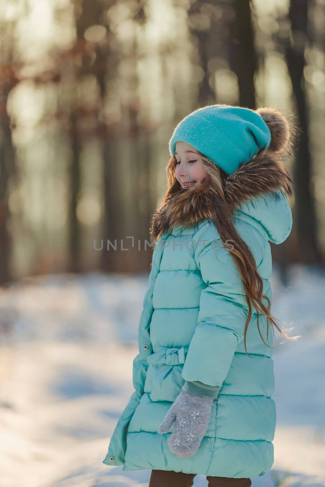 girl in a turquoise squat and a hat in a winter forest, shot vertically