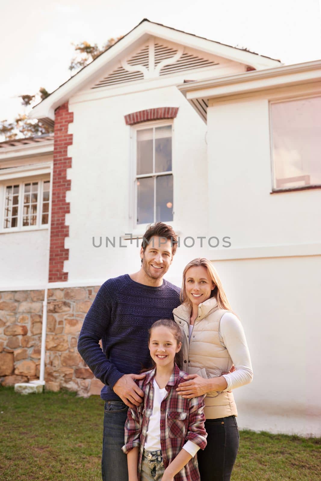 Welcome to our home. A portrait of a happy family posing outside their home. by YuriArcurs