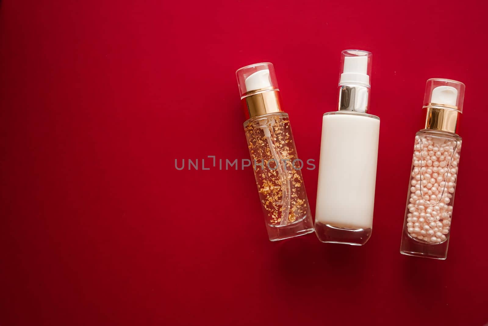 Skincare cosmetics and anti-aging beauty products, luxury skin care bottles, oil, serum and face cream on red background.
