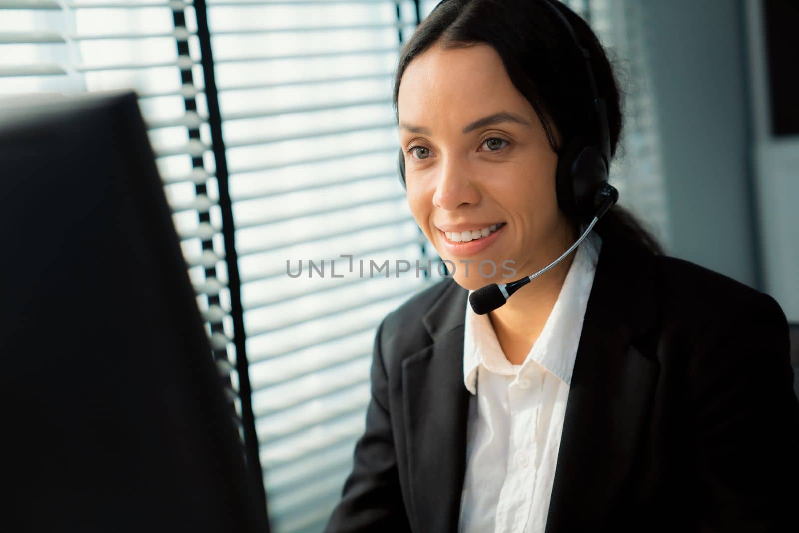 Competent female operator working on computer and while talking with clients. by biancoblue