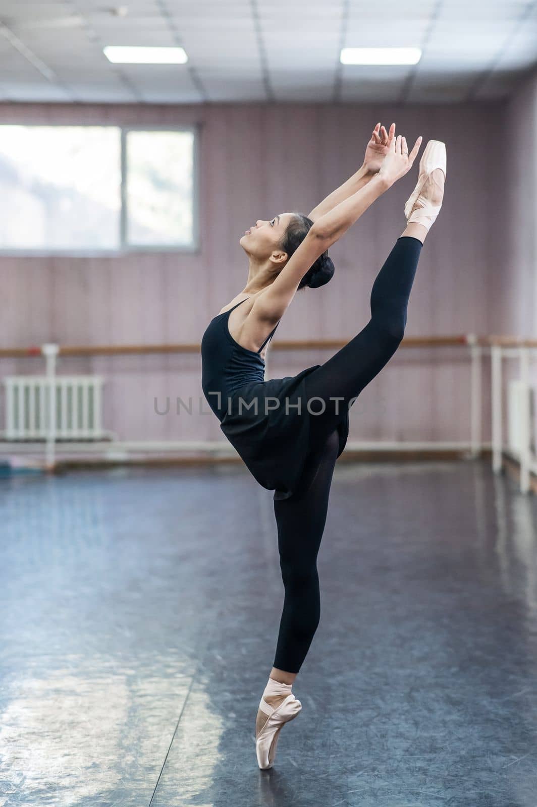 Asian woman dancing in ballet class doing bilman pose