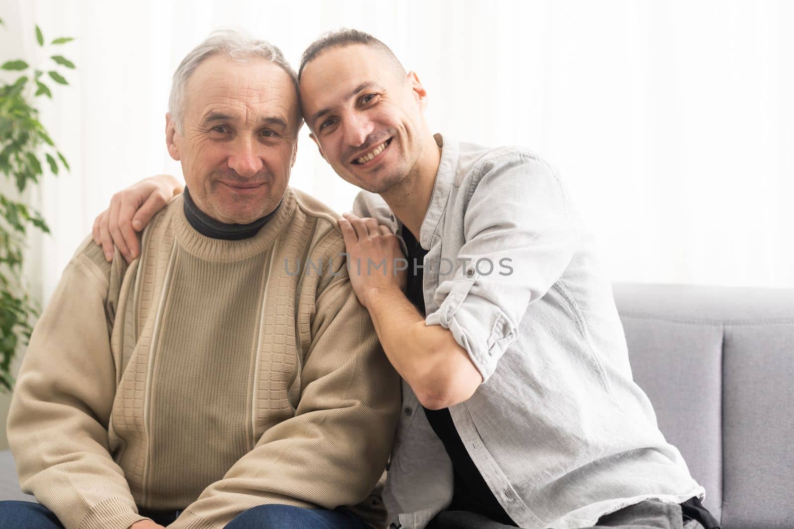 Young adult caucasian son listening and supporting his old elderly senior father at home indoors. Care and love concept. by Andelov13