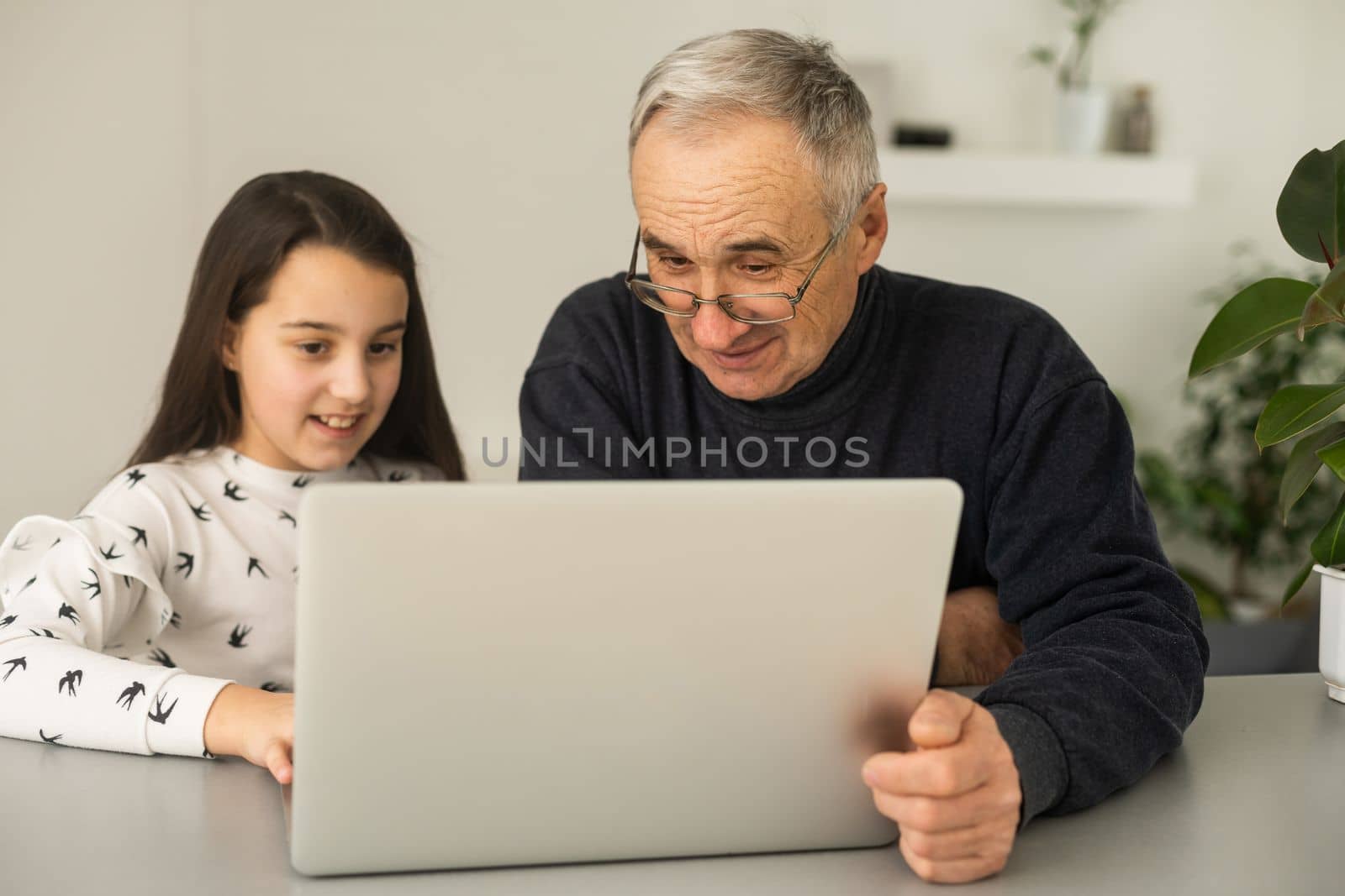 Grandfather and granddaughter spend time together use laptop, browse website, younger generation teach explain to older how to use modern tech concept by Andelov13