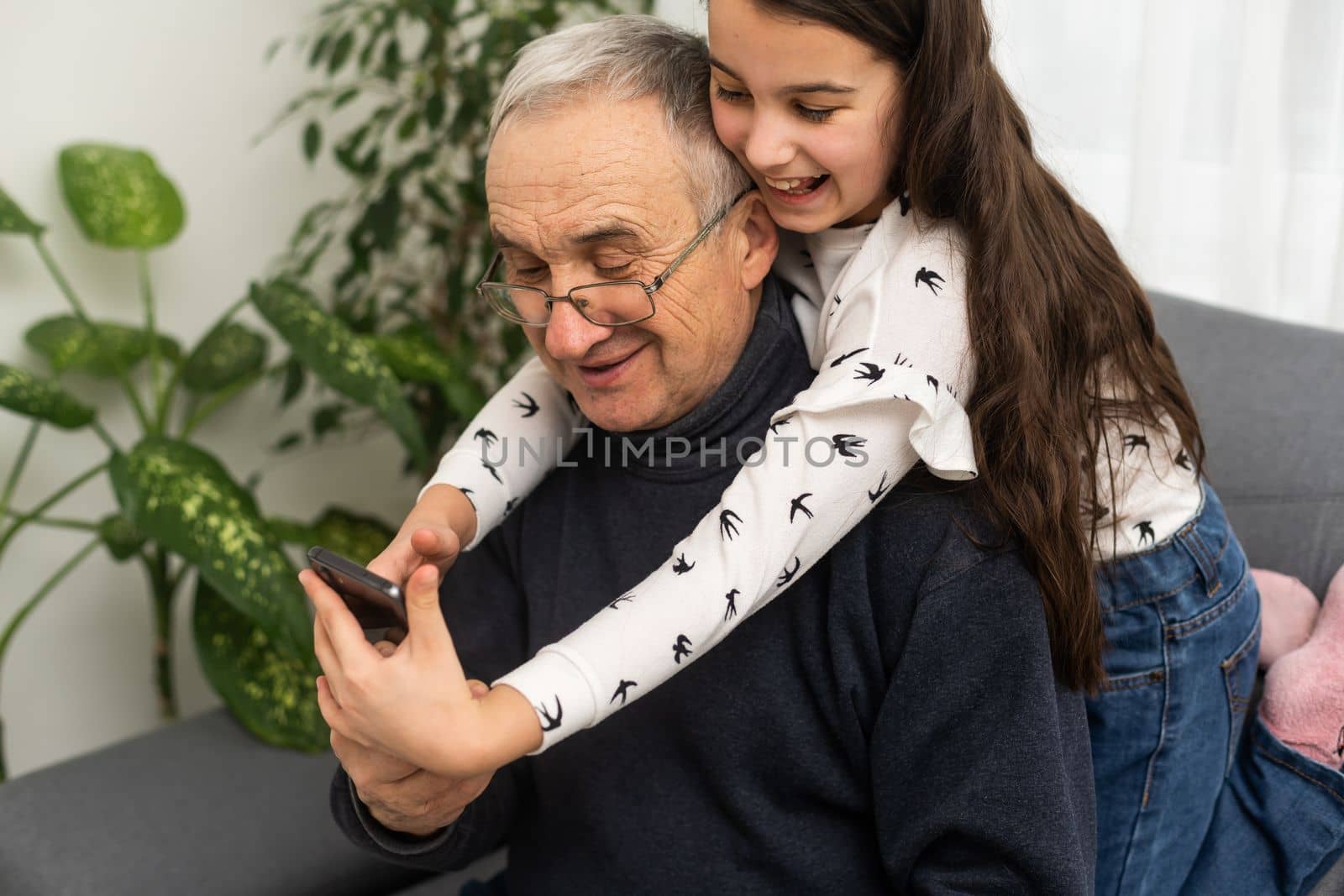 Teenage girl taking photo with mobile phone of herself and her grandfather