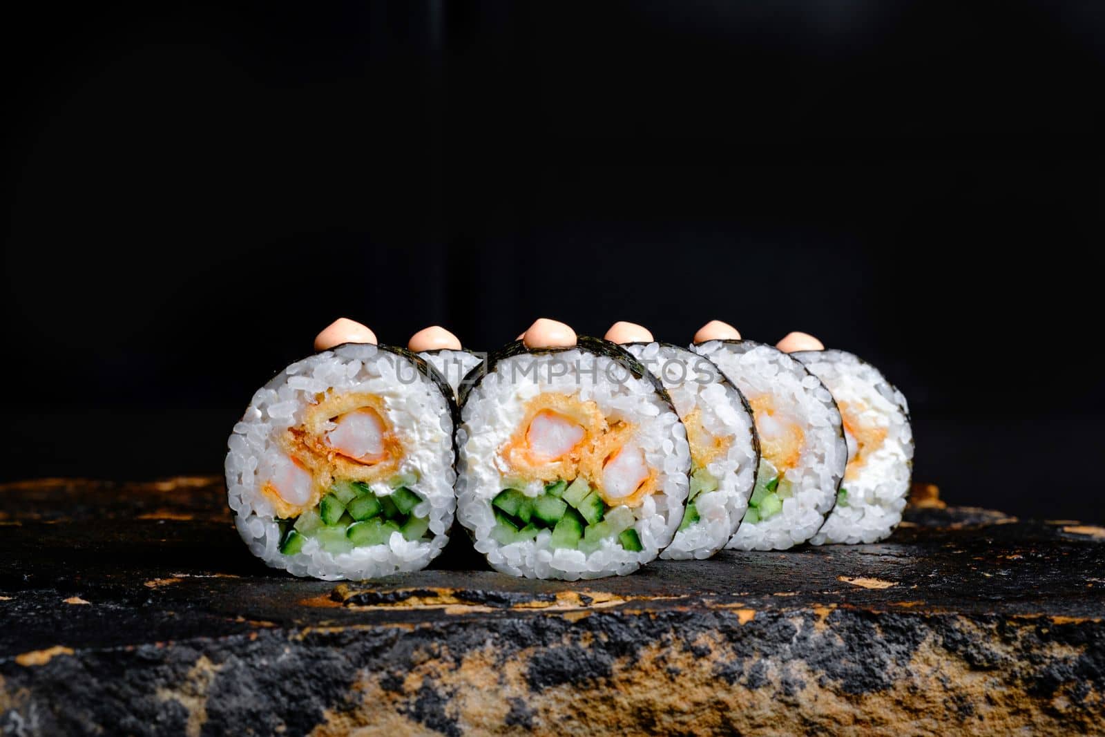 This appetizing photo showcases a sushi roll that is sure to make your mouth water. The roll is expertly crafted and features fresh ingredients, including rice, seaweed, and a variety of tasty fillings. The sushi is elegantly arranged on a stone plate, which contrasts nicely with the vibrant colors of the roll. The photo is perfect for anyone looking to add a touch of sophistication and culinary flair to their marketing materials, blog posts, or social media accounts. Whether you are a food blogger, restaurant owner, or just a lover of sushi, this photo is sure to delight your audience and leave them craving more