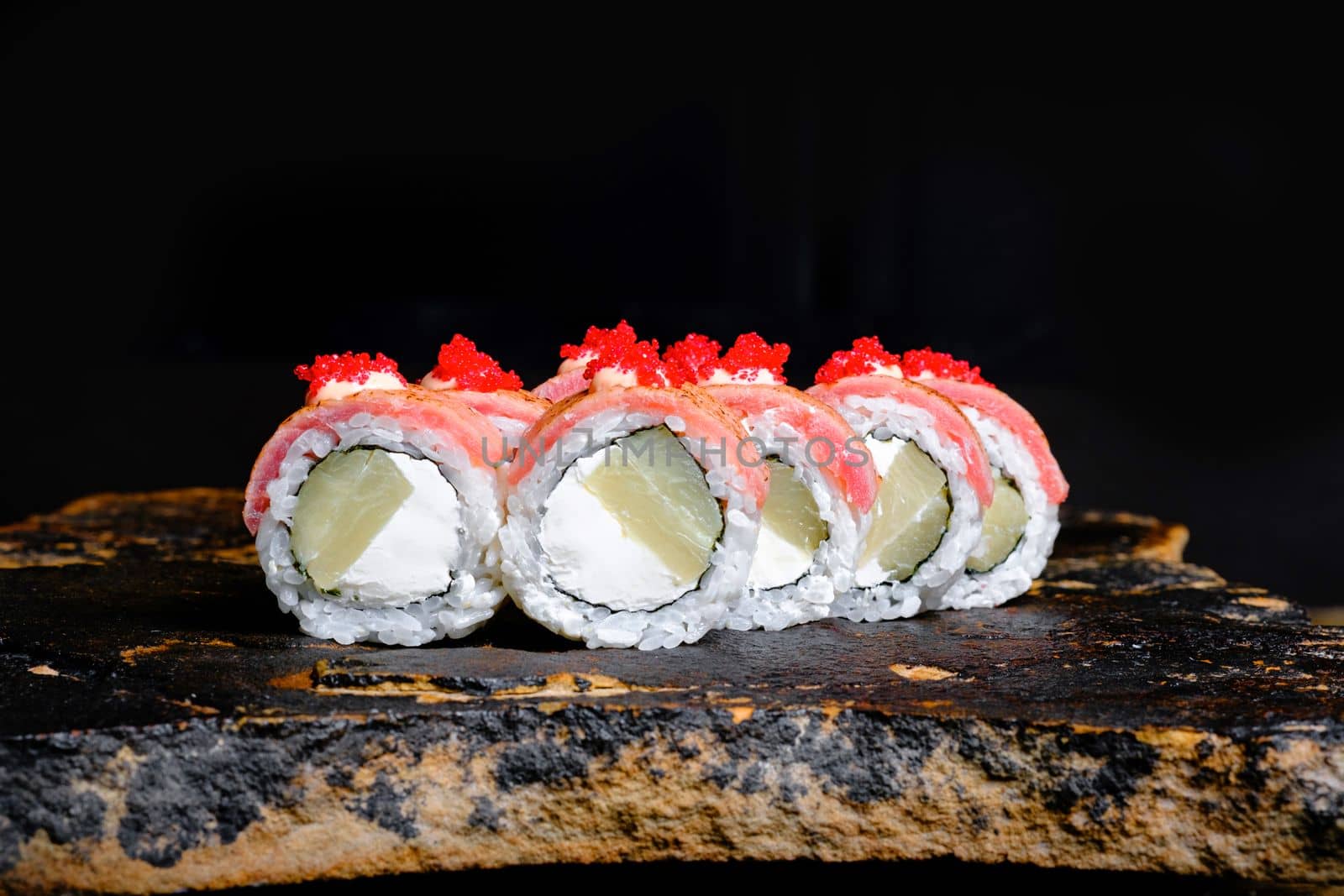 This appetizing photo showcases a sushi roll that is sure to make your mouth water. The roll is expertly crafted and features fresh ingredients, including rice, seaweed, and a variety of tasty fillings. The sushi is elegantly arranged on a stone plate, which contrasts nicely with the vibrant colors of the roll. The photo is perfect for anyone looking to add a touch of sophistication and culinary flair to their marketing materials, blog posts, or social media accounts. Whether you are a food blogger, restaurant owner, or just a lover of sushi, this photo is sure to delight your audience and leave them craving more