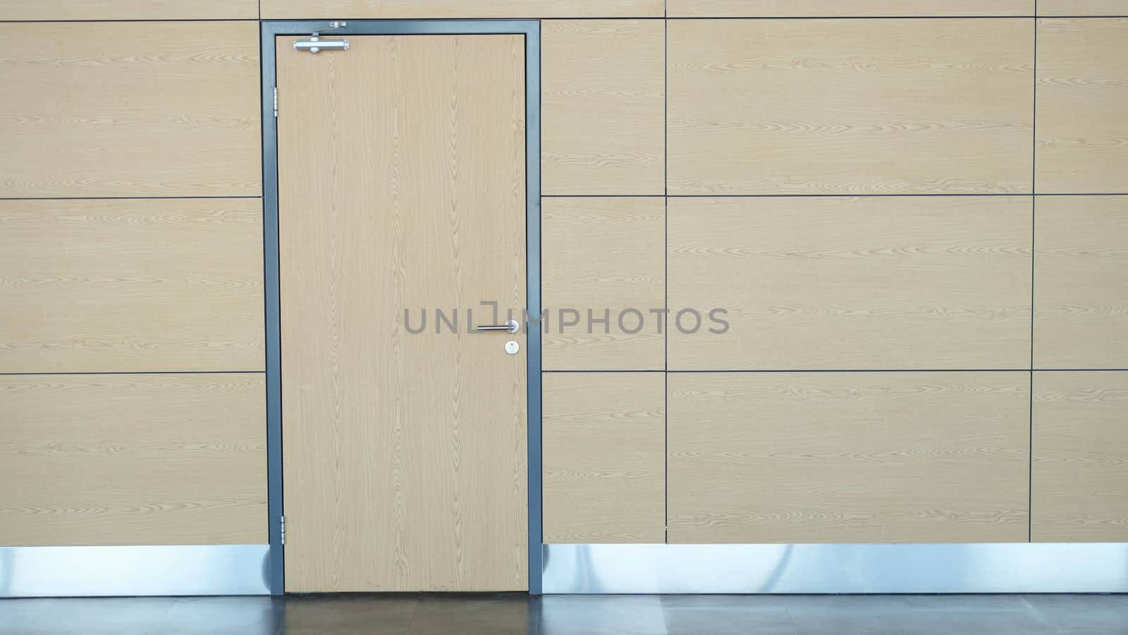 Interior of long wall with light brown door airport or train station. One stylish door in business center