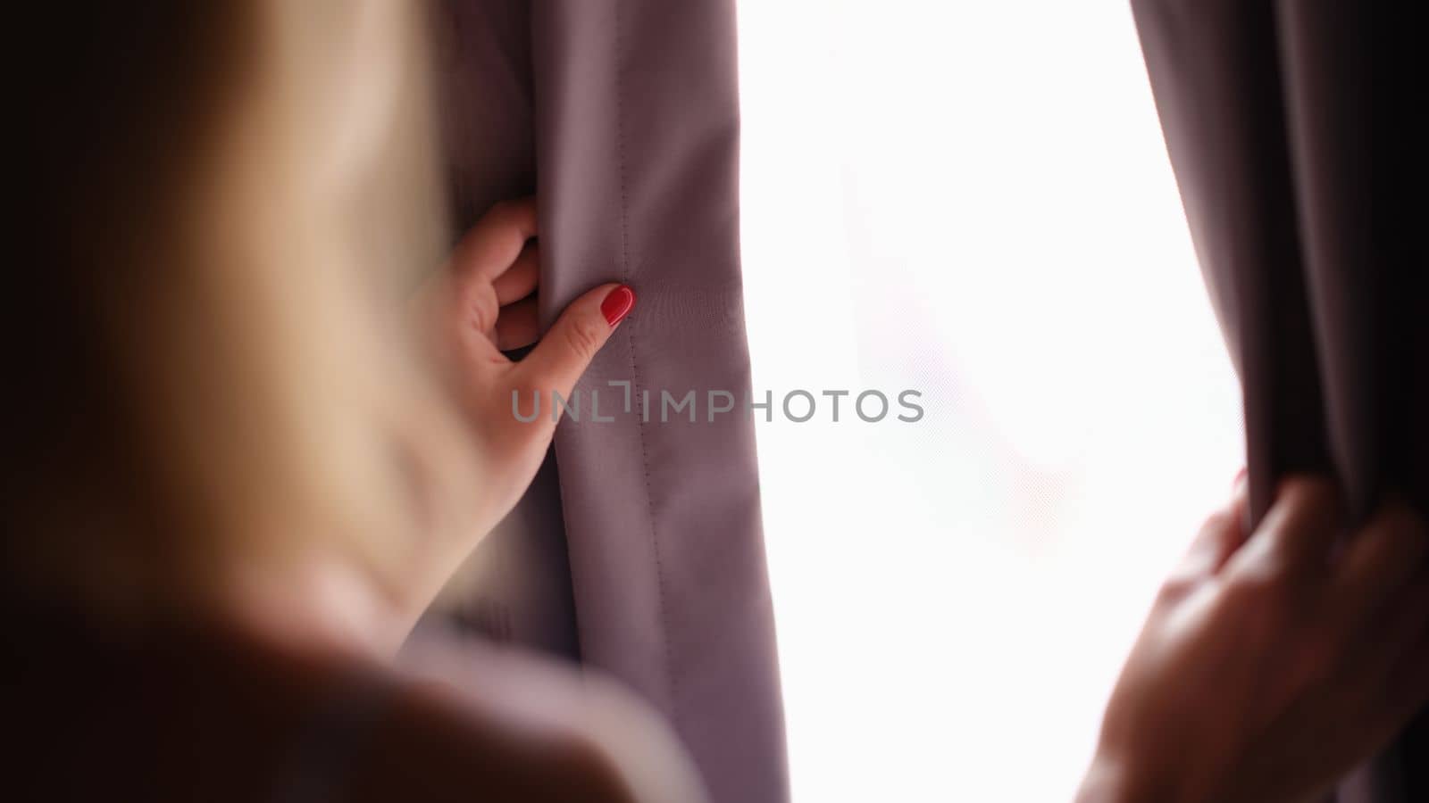 Woman opens curtains at home in morning closeup. Woman opens curtains and looks out window