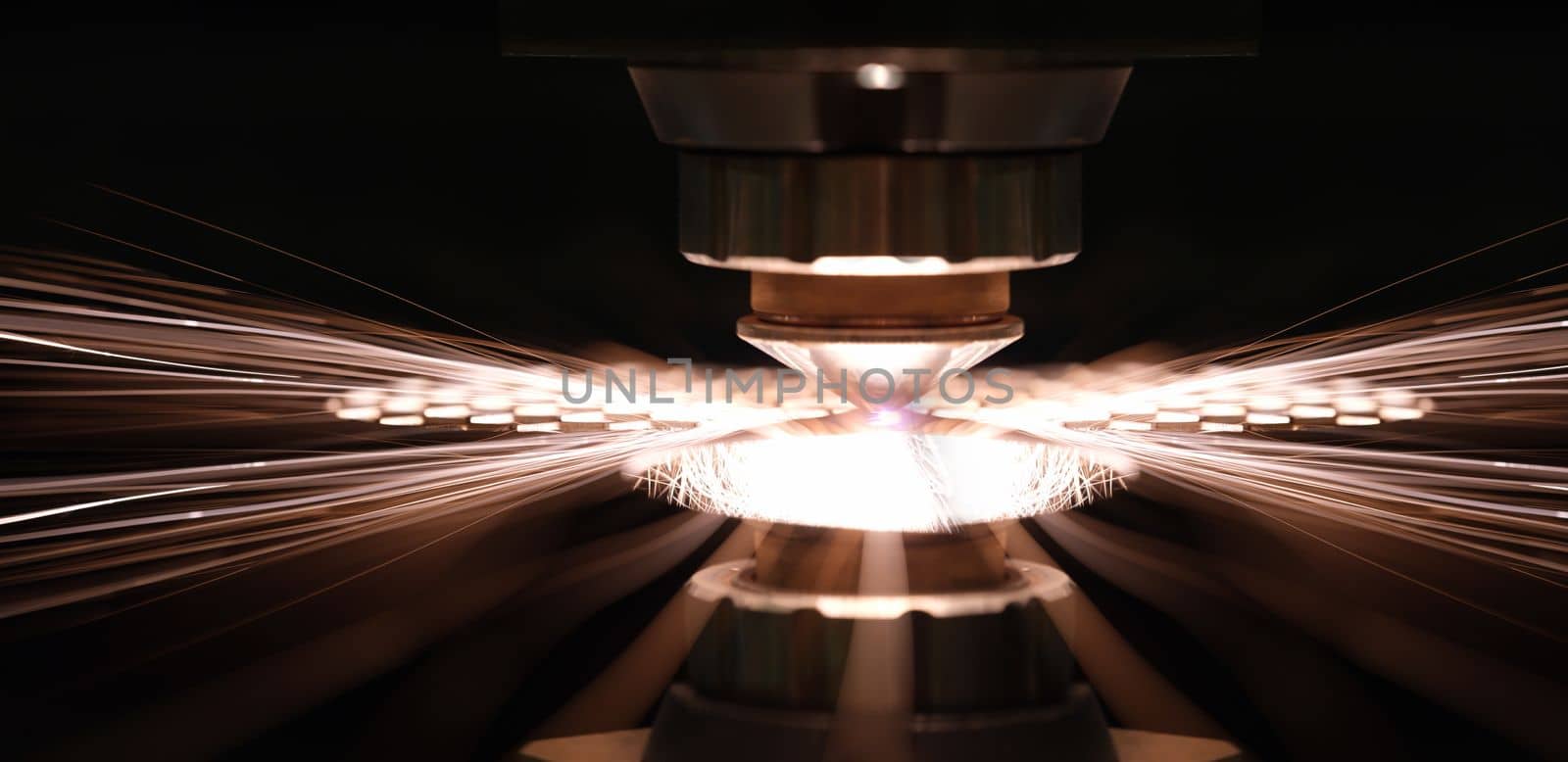 Laser cutting of metal sheet in production closeup. Sparks fly out machine head for metal processing