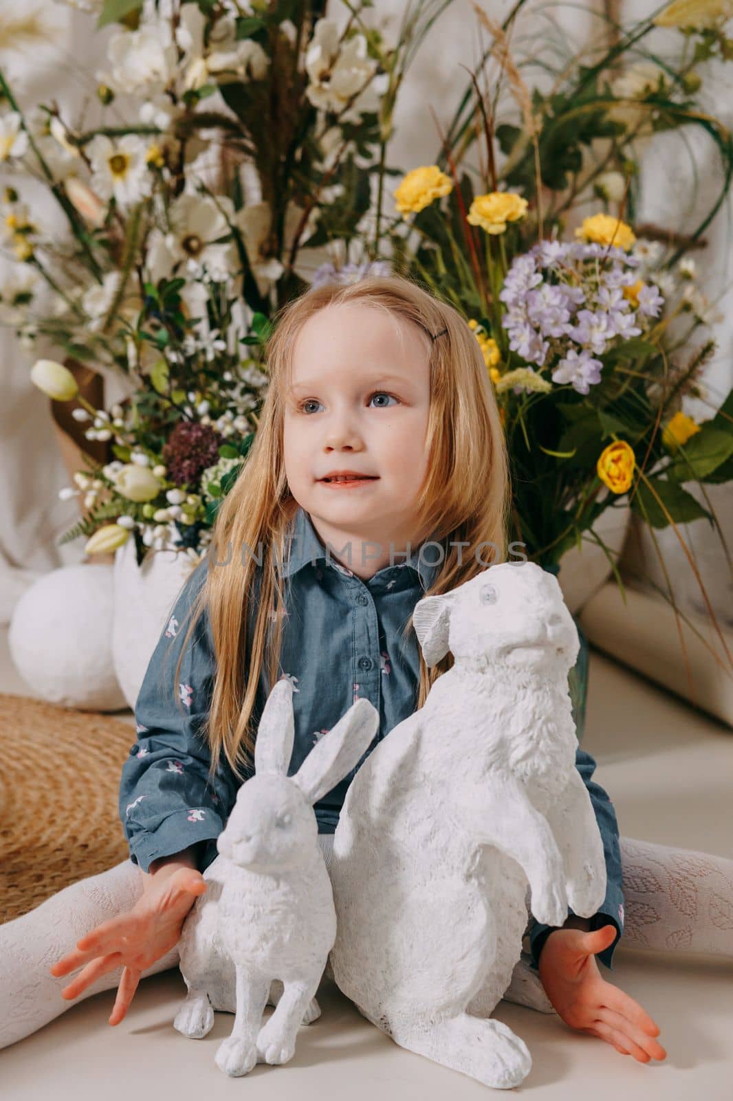 Two girls in a beautiful Easter photo zone with flowers, eggs, chickens and Easter bunnies. Happy Easter holiday. by Annu1tochka