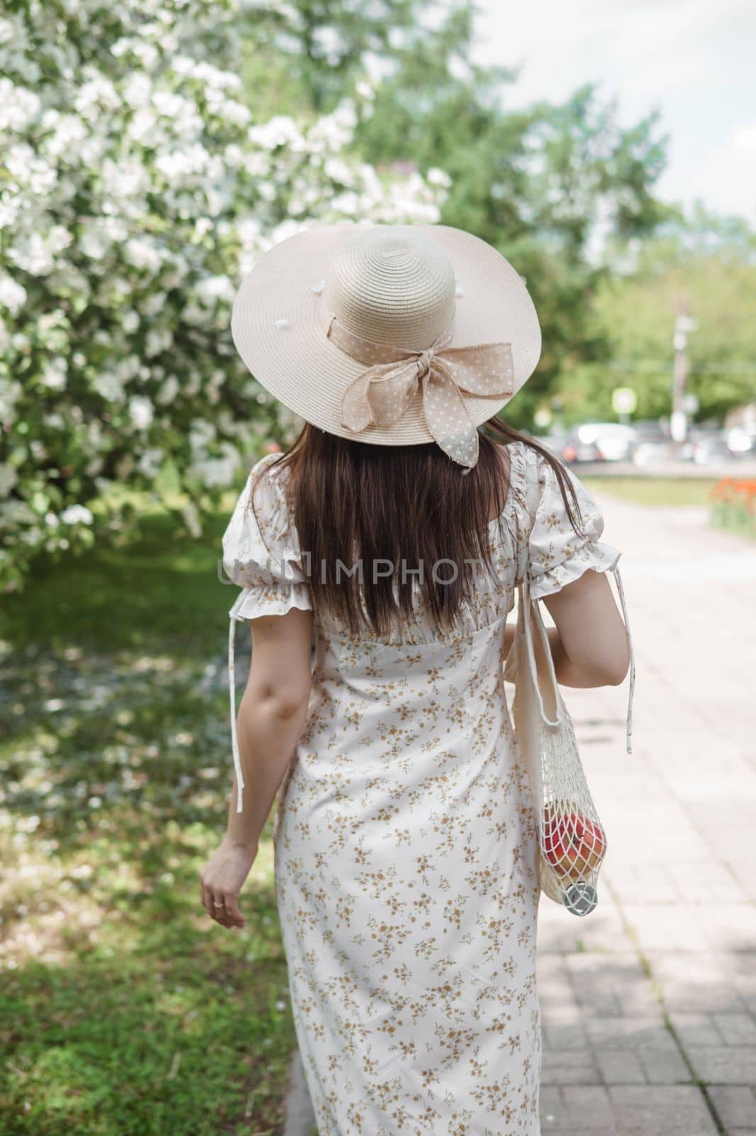 An attractive long-haired woman walks in the spring in the park of blooming apple trees. Spring portrait of a woman