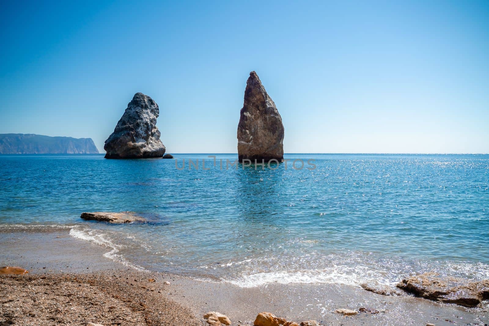 Two rocks stick out of the water in the middle of the turquoise sea. Scenic ocean views. High quality photo. Like in Iceland.