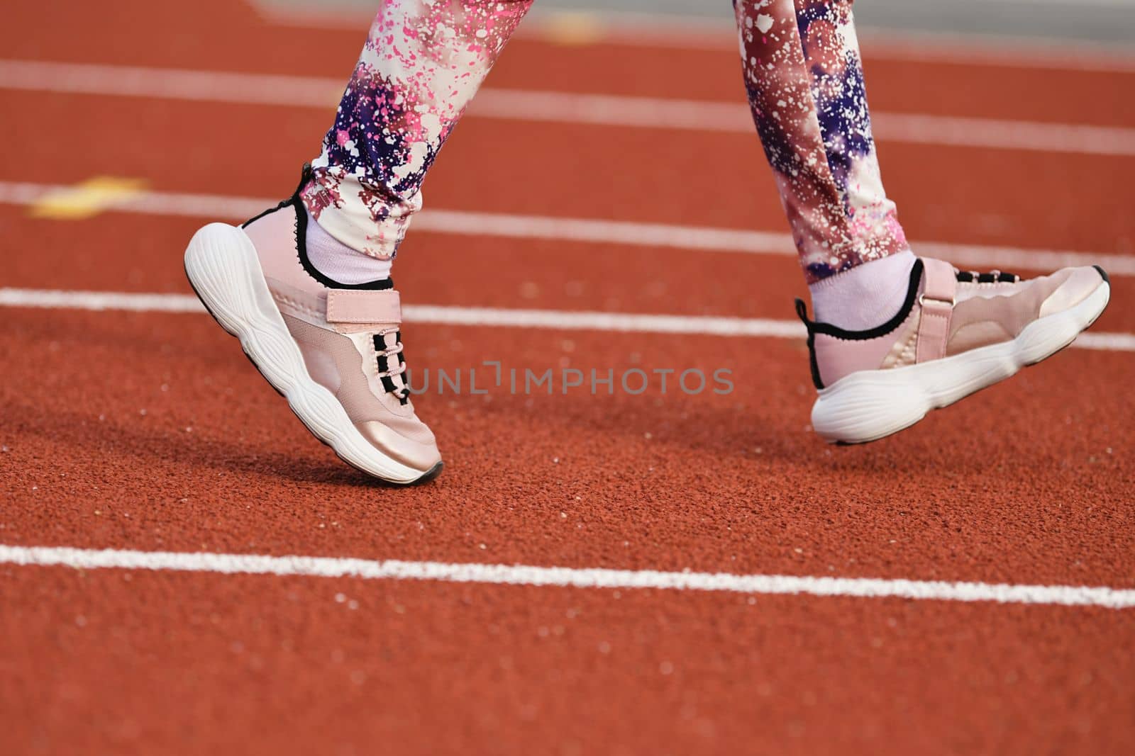 Girl in pink sneakers runs in the stadium