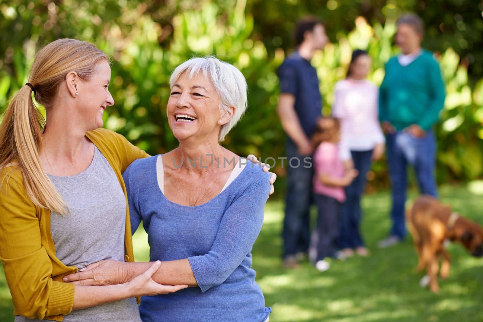 Family comes first. Portrait of a young woman hugging her mother with the rest of the family in the background