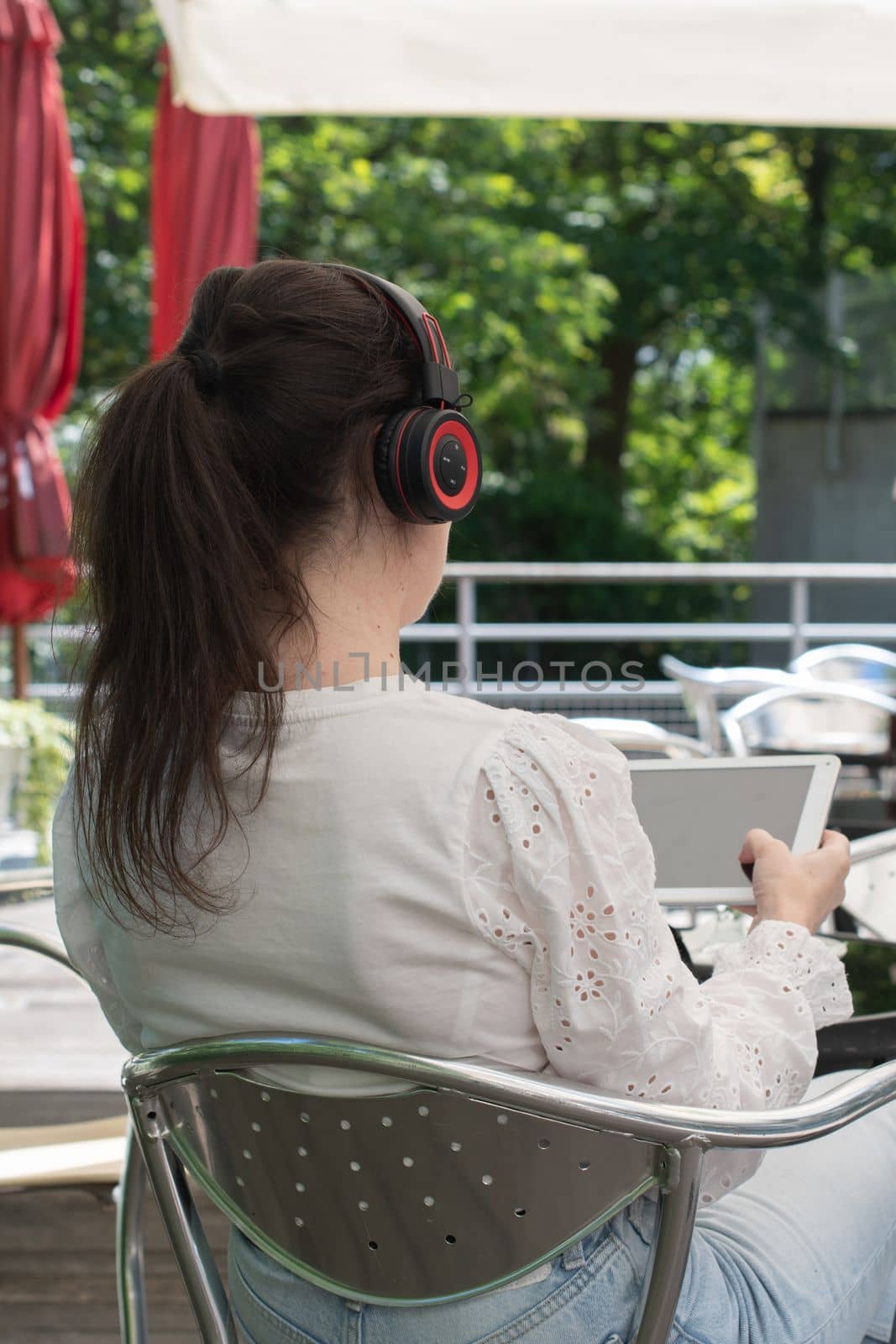 Sad girl listens to music from a tablet at a table in a cafe, High quality photo