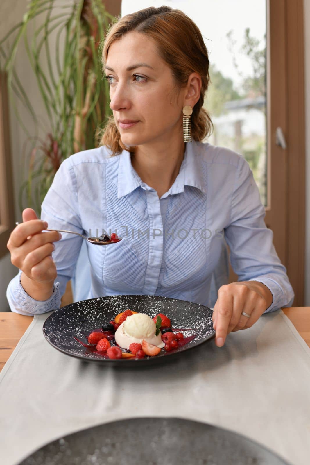 Woman eating panna cotta in a restaurant