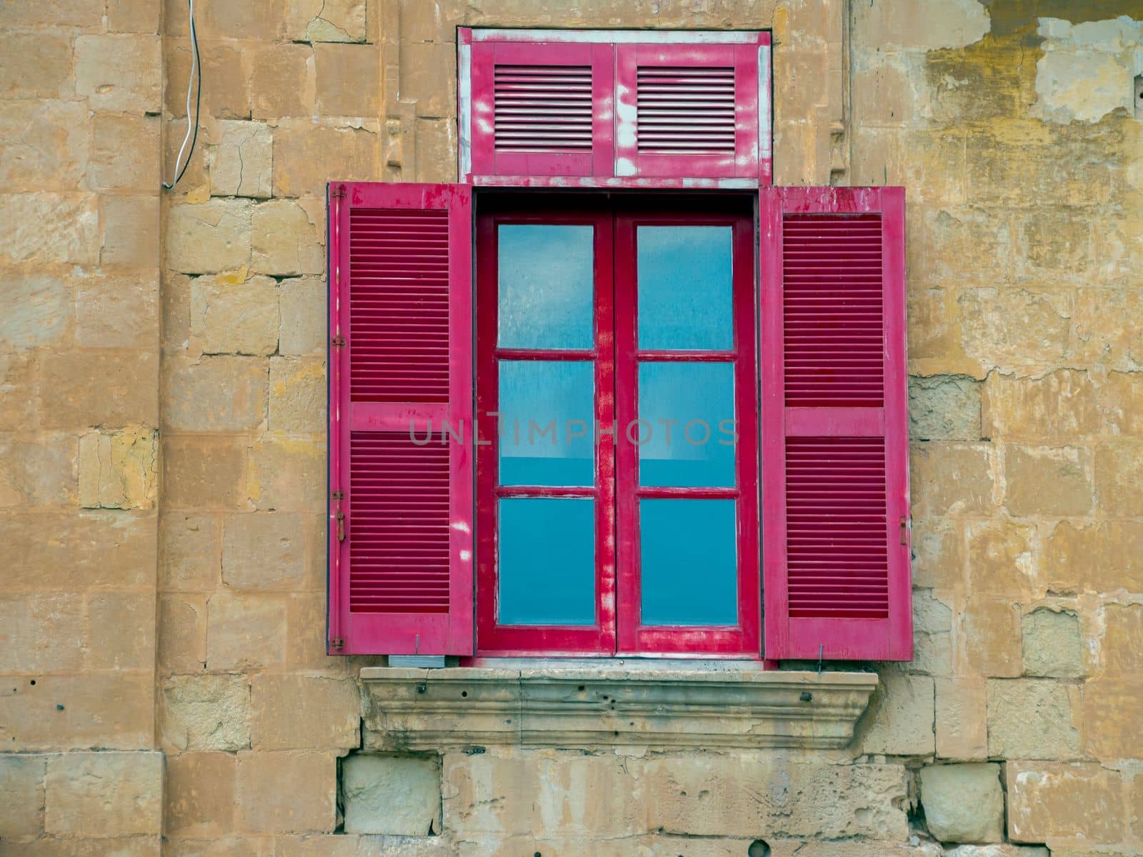 Fragment of the building's facade with traditional wooden ornate balconies painted in Valletta, Malta. High quality photo