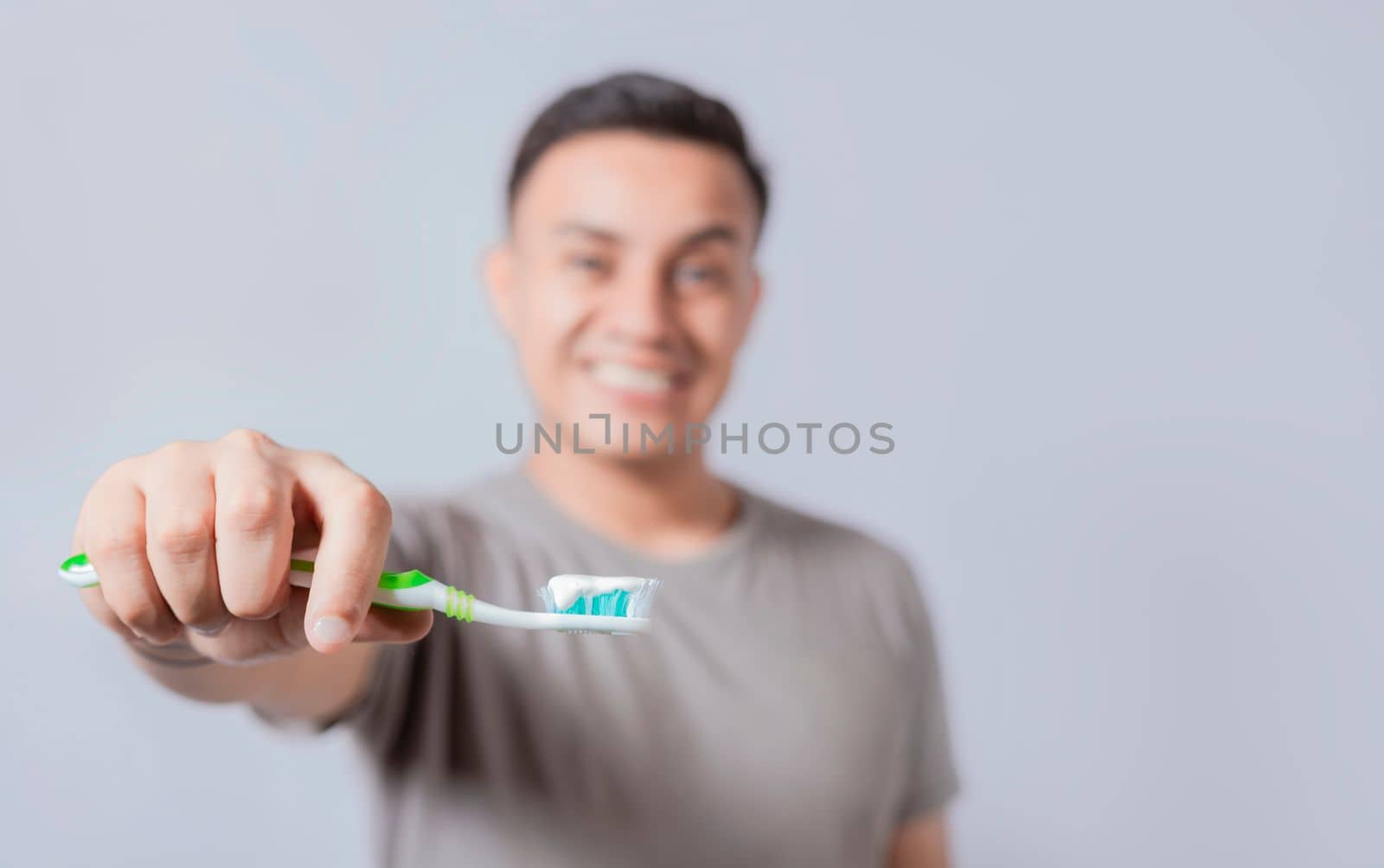 Smiling young man showing toothbrush with toothpaste isolated. Smiling people holding toothbrush with toothpaste with copy space, Smiling man showing a toothbrush in the foreground