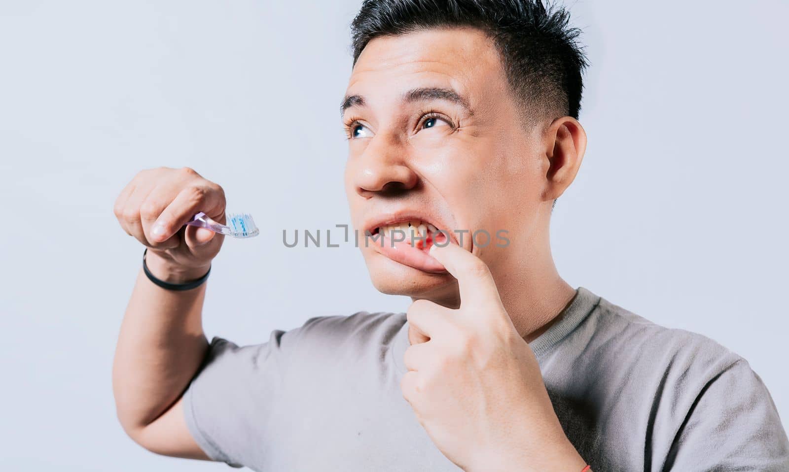 Man holding toothbrush with gum pain isolated, People holding toothbrush with gum problem isolated. Young man with gingivitis holding toothbrush, People holding toothbrush with gum pain by isaiphoto