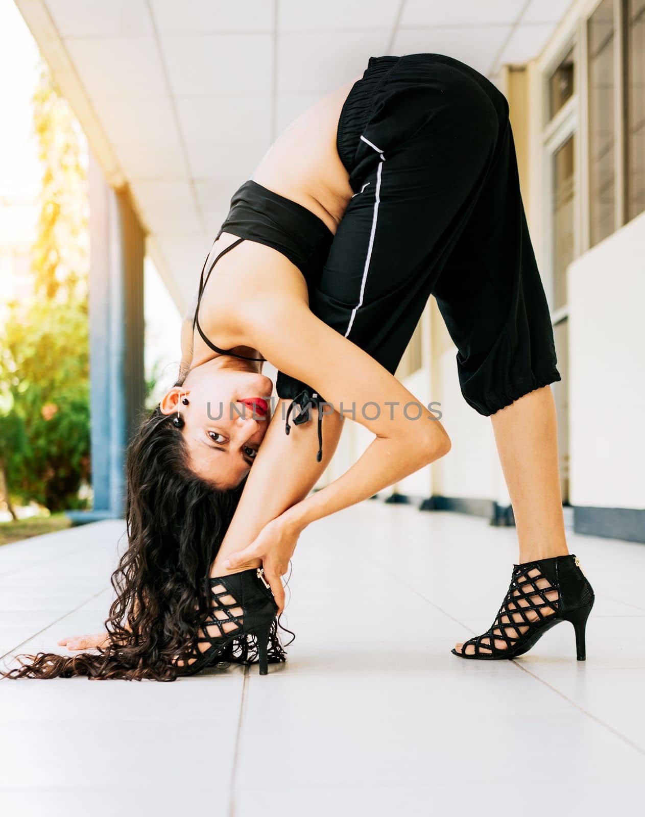 Portrait of dance girl in heels doing gymnastics poses. Woman dancer in heels doing flexibilities poses. Dance young woman doing acrobatics and flexibilities in high heels outdoors