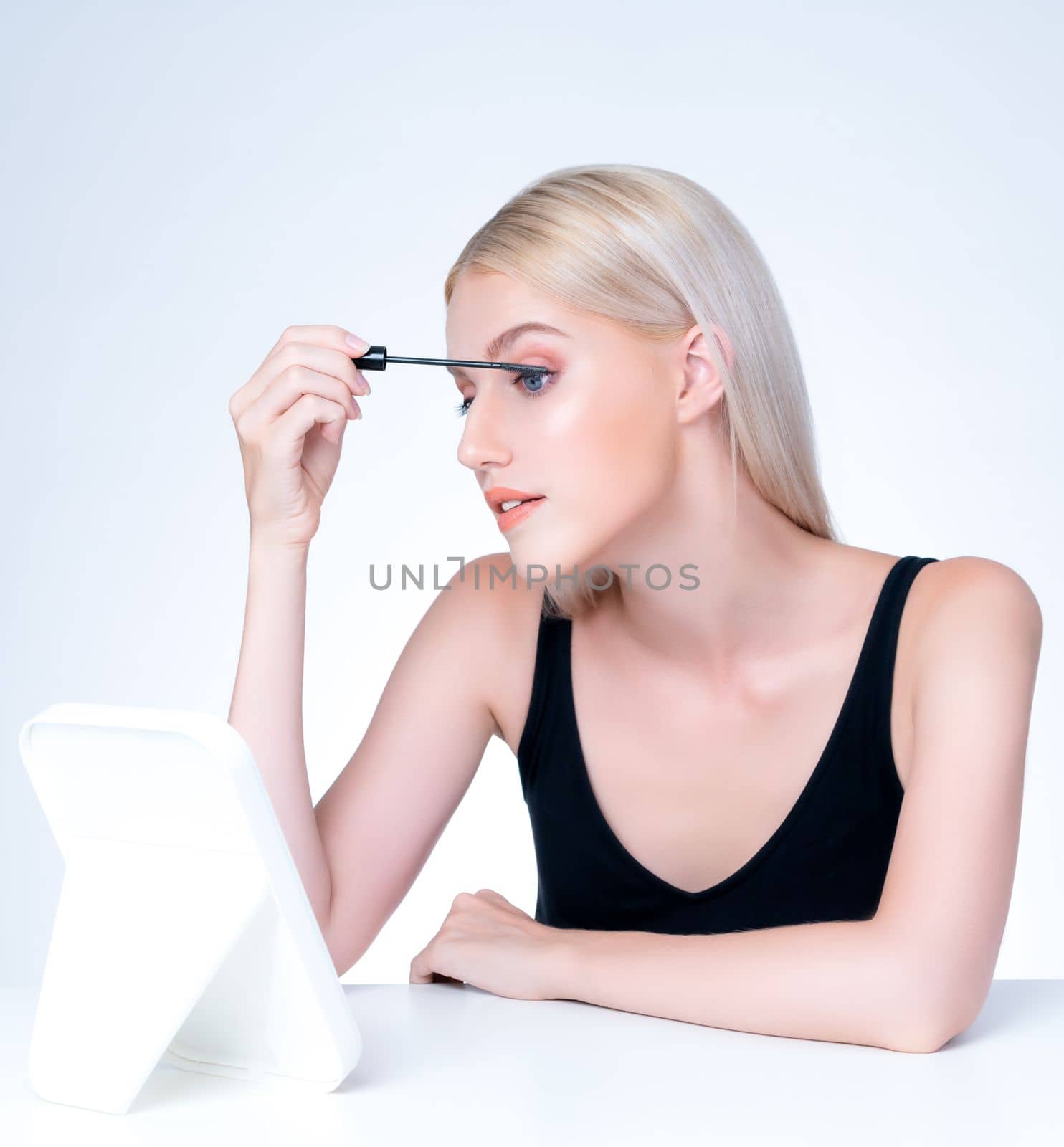 Personable woman with blond hair putting black mascara with brush in hand on long thick eyelash. Perfect fashionable cosmetic clean facial skin with beautiful eye young woman in high resolution.