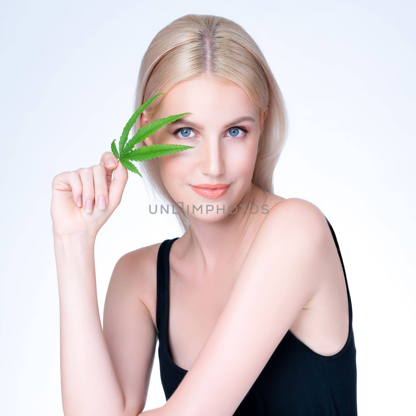 Personable white blond hair woman holding CBD leaf in isolated background. by biancoblue