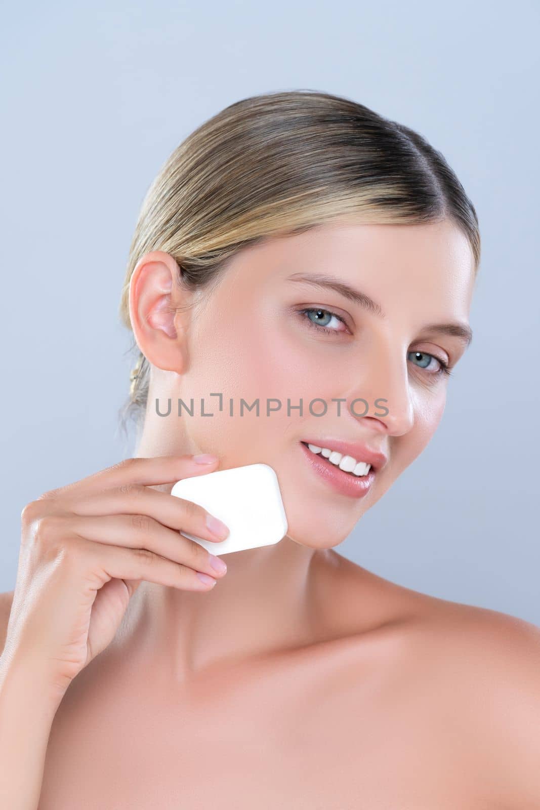 Closeup alluring beautiful female model applying powder puff for facial makeup concept. Portrait of flawless perfect cosmetic skin woman put powder foundation on her face in isolated background.