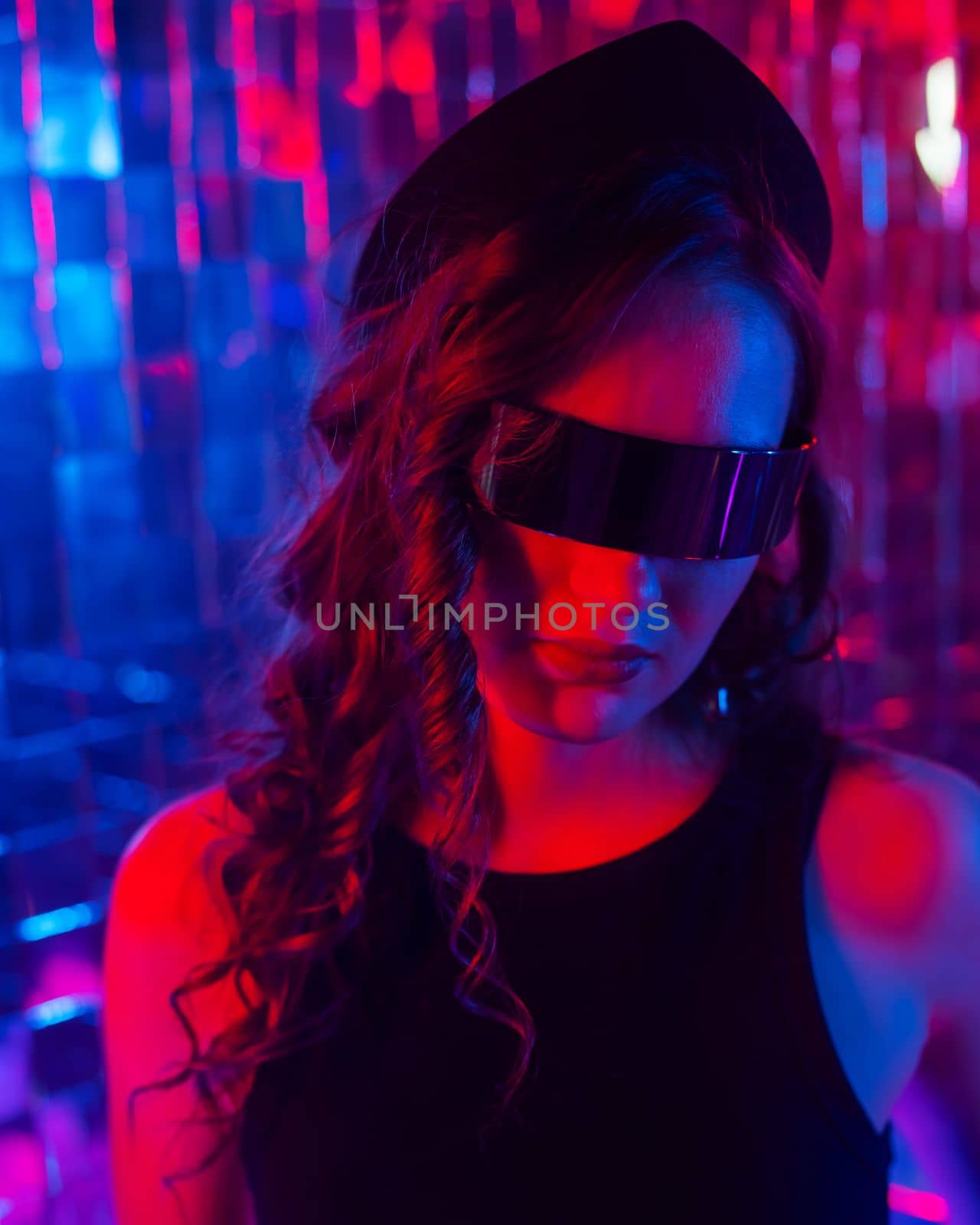 Close-up portrait of a caucasian woman in sunglasses in neon light against a mirror wall