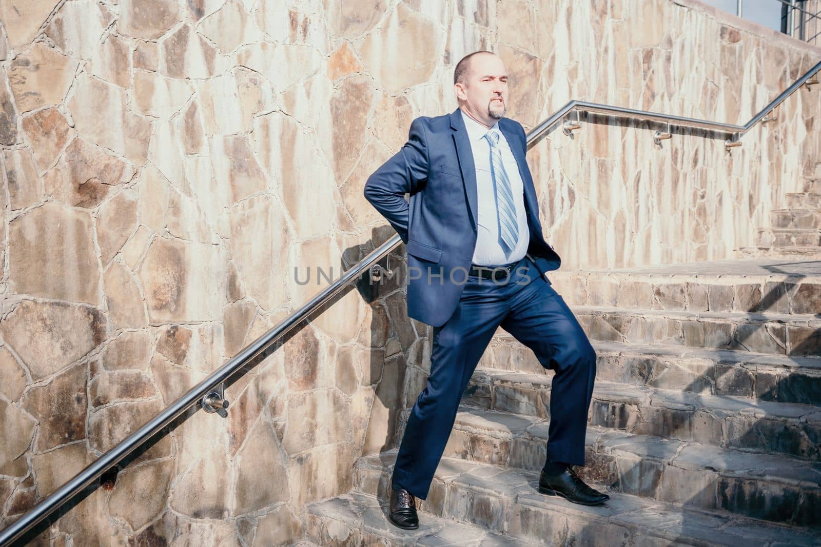 Portrait of a senior professional man in a suit with various problems. A middle-aged businessman with a briefcase descends the stairs.