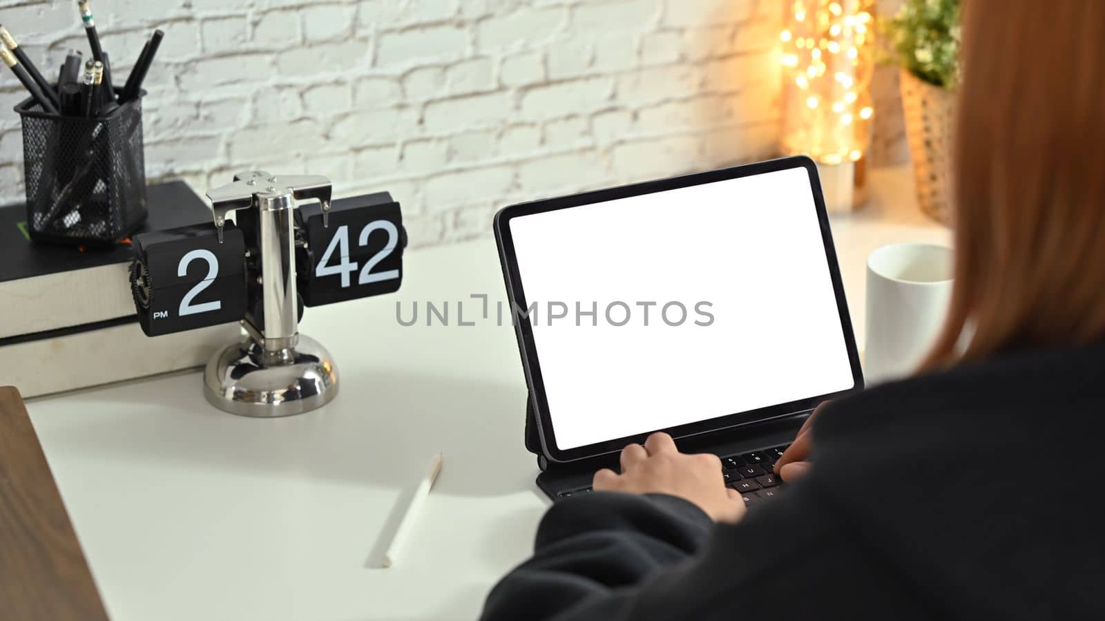 View over shoulder of young creative woman using digital tablet on white working desk.