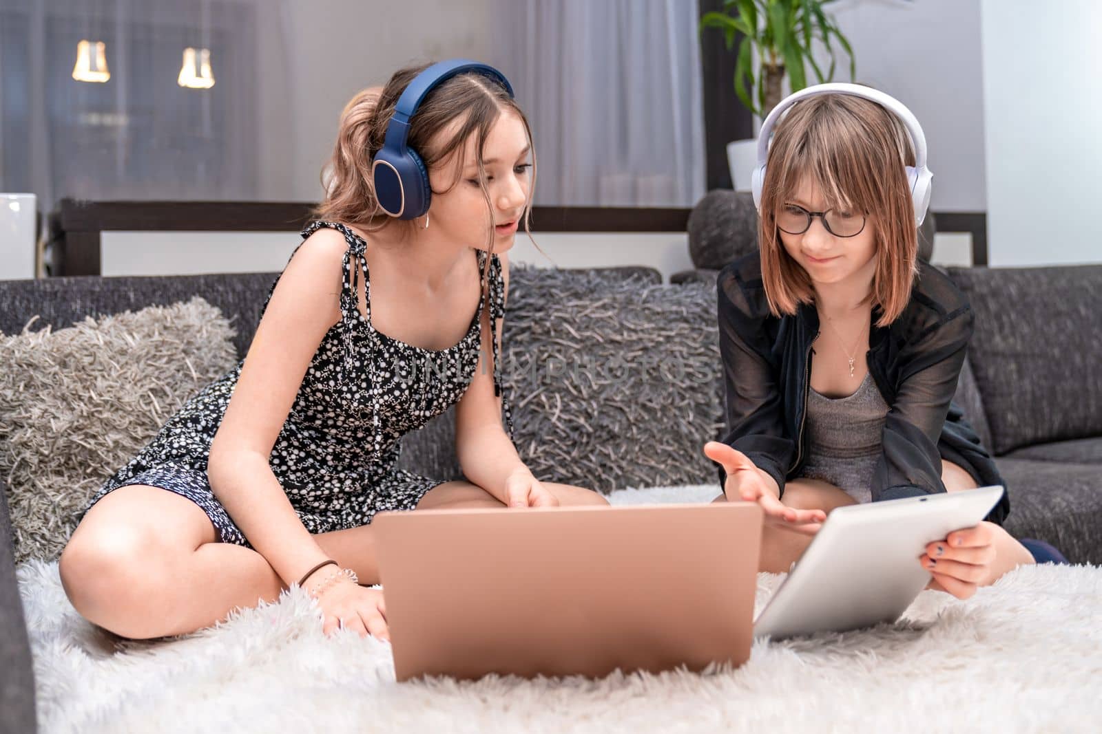 children have fun at home with modern technology, they use headphones and a laptop. High quality photo