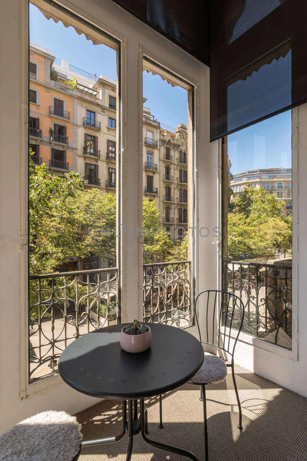 Amazing view of two chairs and coffee table on covered terrace with stunning views of the Barcelona area on sunny warm summer day. Concept of an apartment for a young family. by apavlin