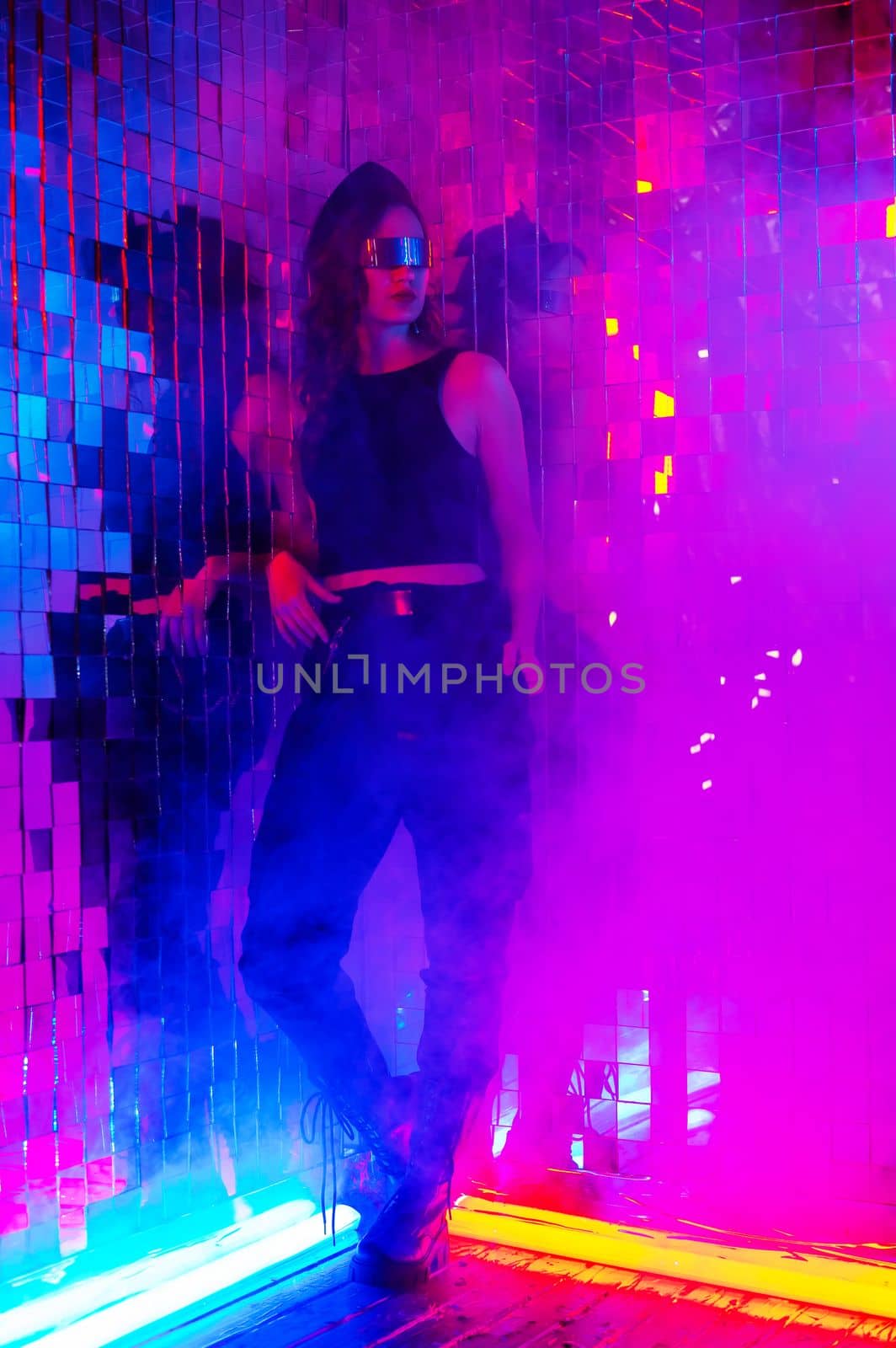 Portrait of a caucasian woman in sunglasses in neon light against a mirror wall