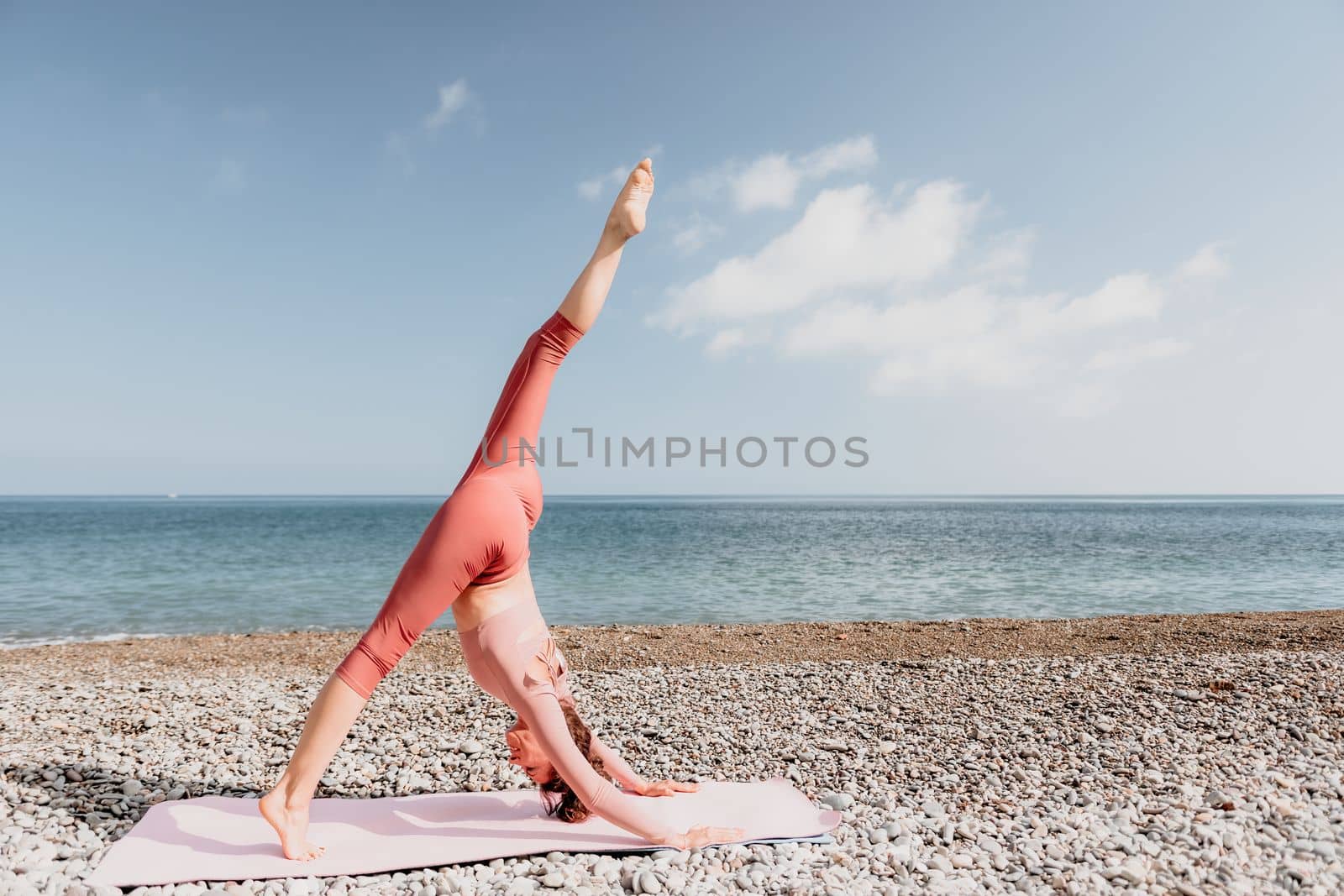 Middle aged well looking woman with black hair doing Pilates with the ring on the yoga mat near the sea on the pebble beach. Female fitness yoga concept. Healthy lifestyle, harmony and meditation.