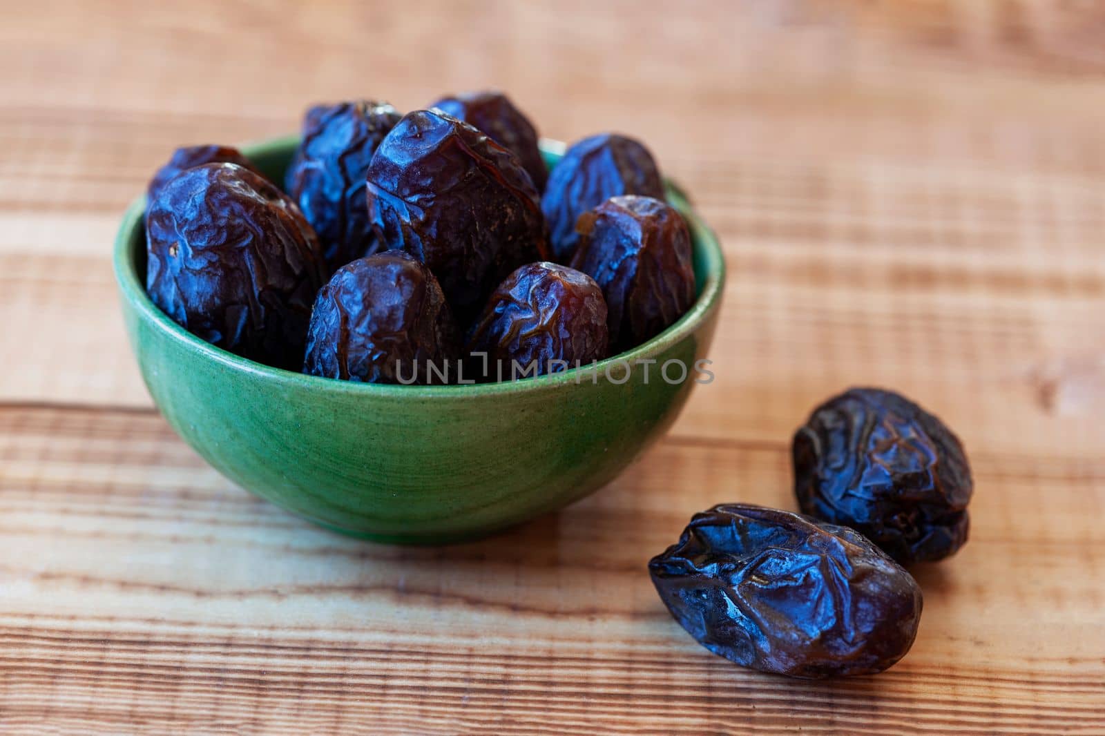 bowl of date fruits on a wooden table, side view
