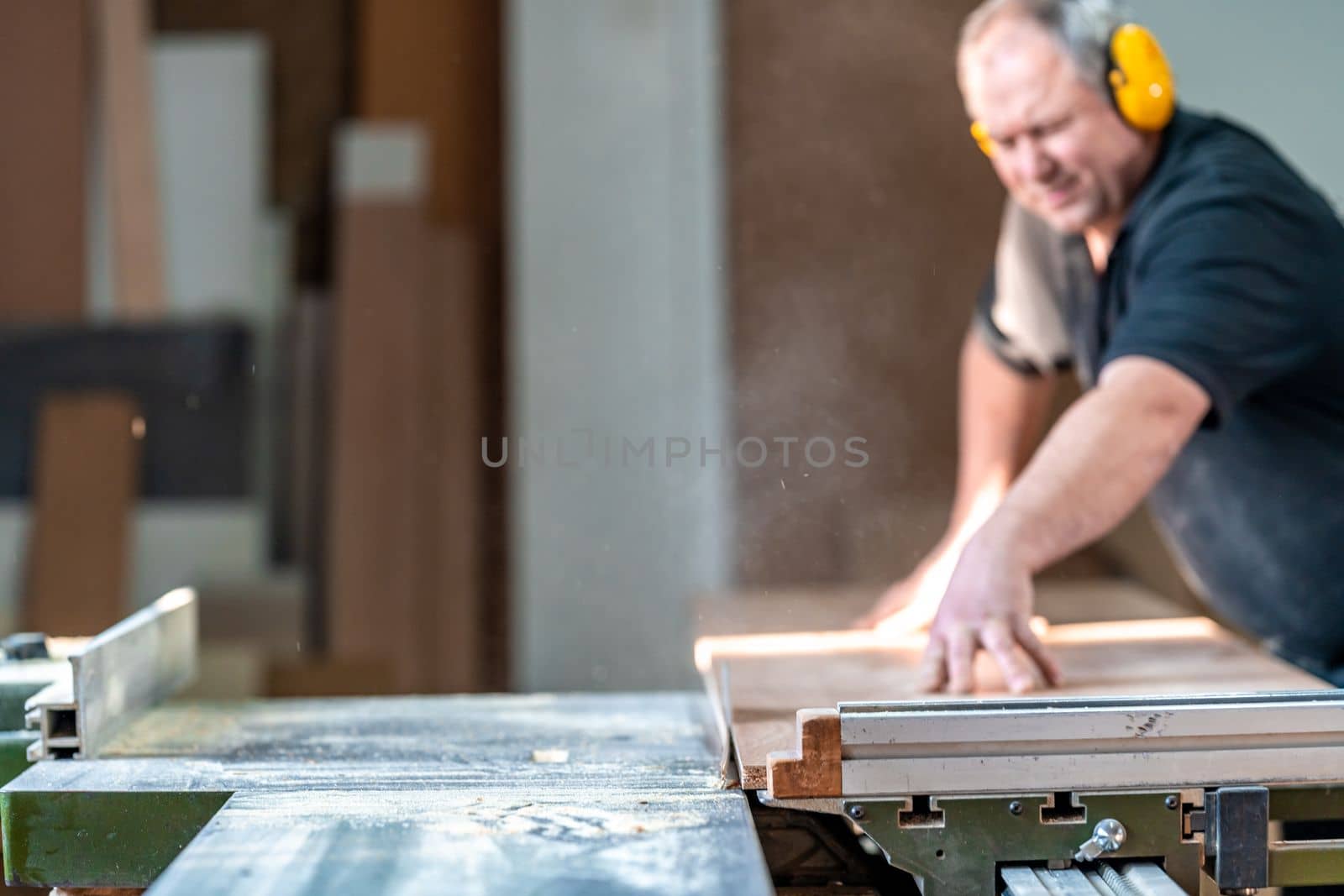craftsman cuts a laminate board on a saw in a joinery by Edophoto