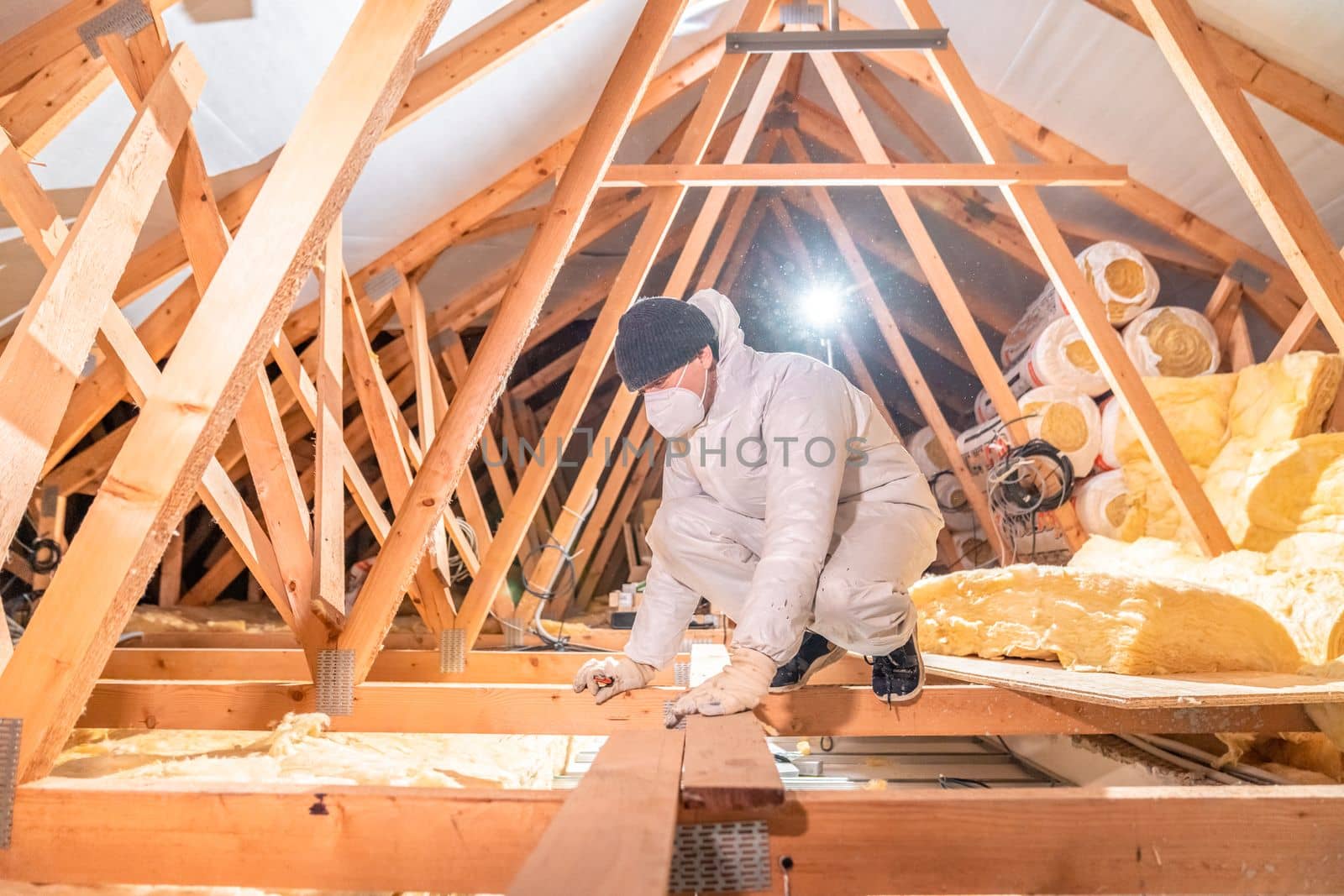 a man insulates the roof and ceiling of the house with glass wool