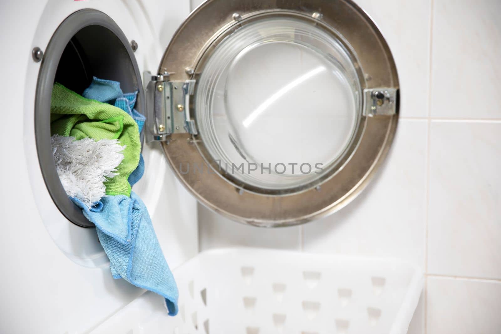 Laundry concept. white and modern washing machine with open door standing inside bright apartment or house light interior close up housekeeping
