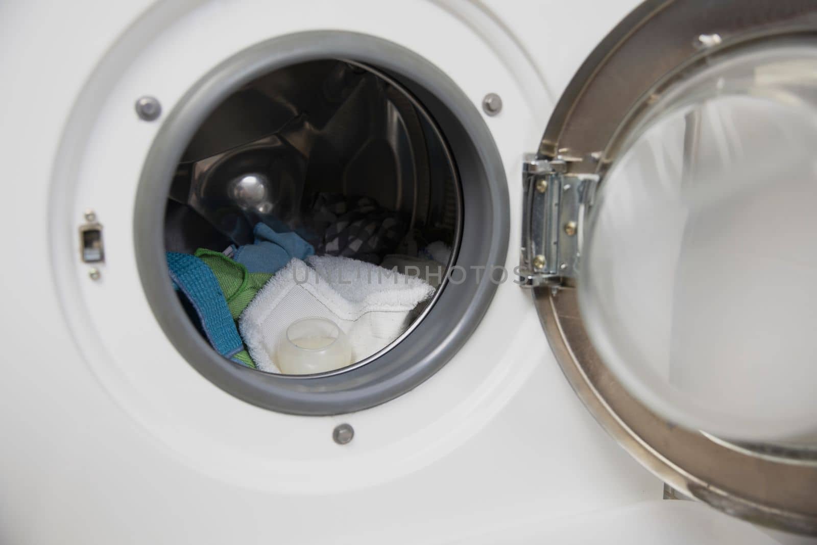 Laundry concept. white and modern washing machine with open door standing inside bright apartment or house light interior close up housekeeping