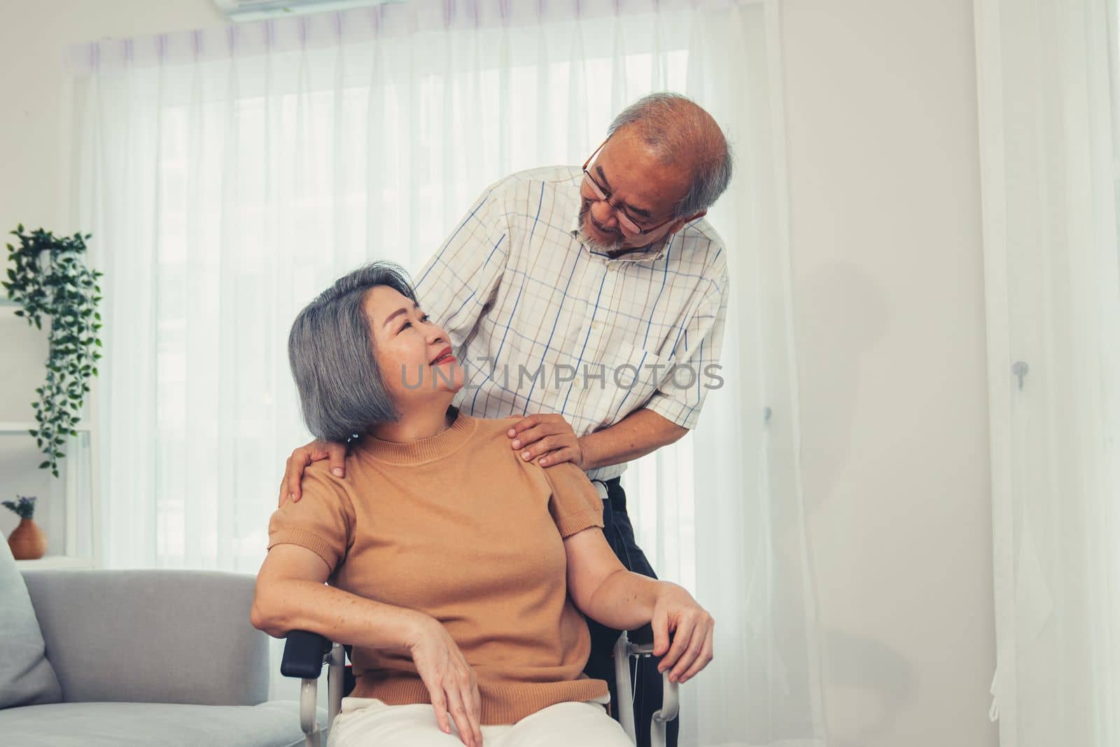 A contented senior couple and their in-home nurse. Elderly female in wheelchair with her young caregiver.