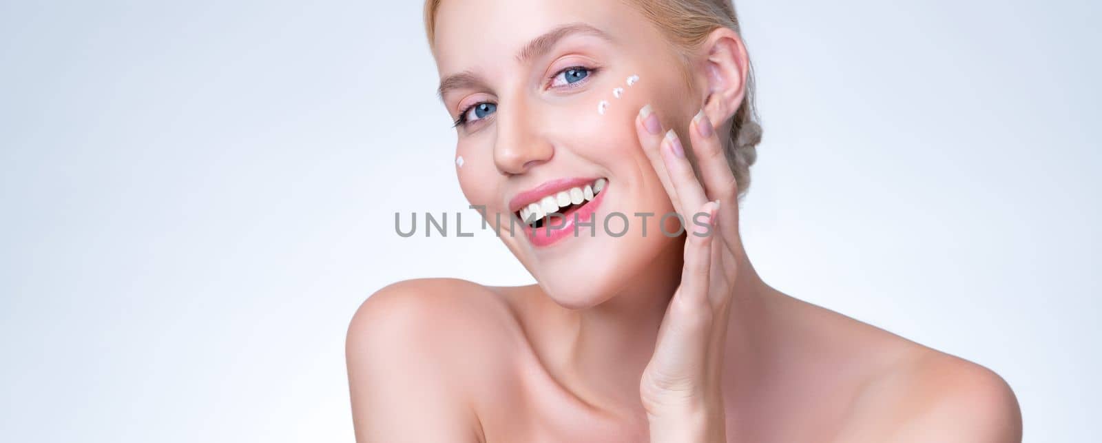 Personable woman applying moisturizer cream on her face for perfect skin by biancoblue