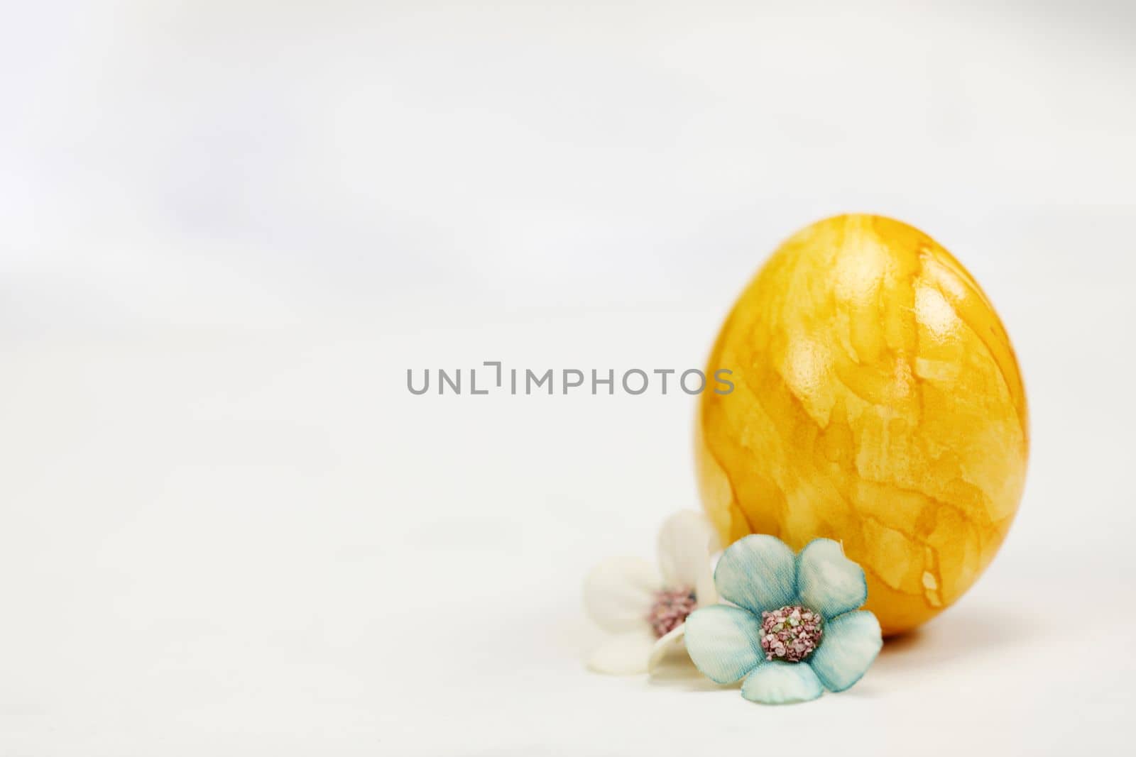 Easter eggs painted in pastel colors on a white background with copy space and cute spring flowers, Happy Easter Holiday concept with space for text. Yellow pink and blue by Annebel146