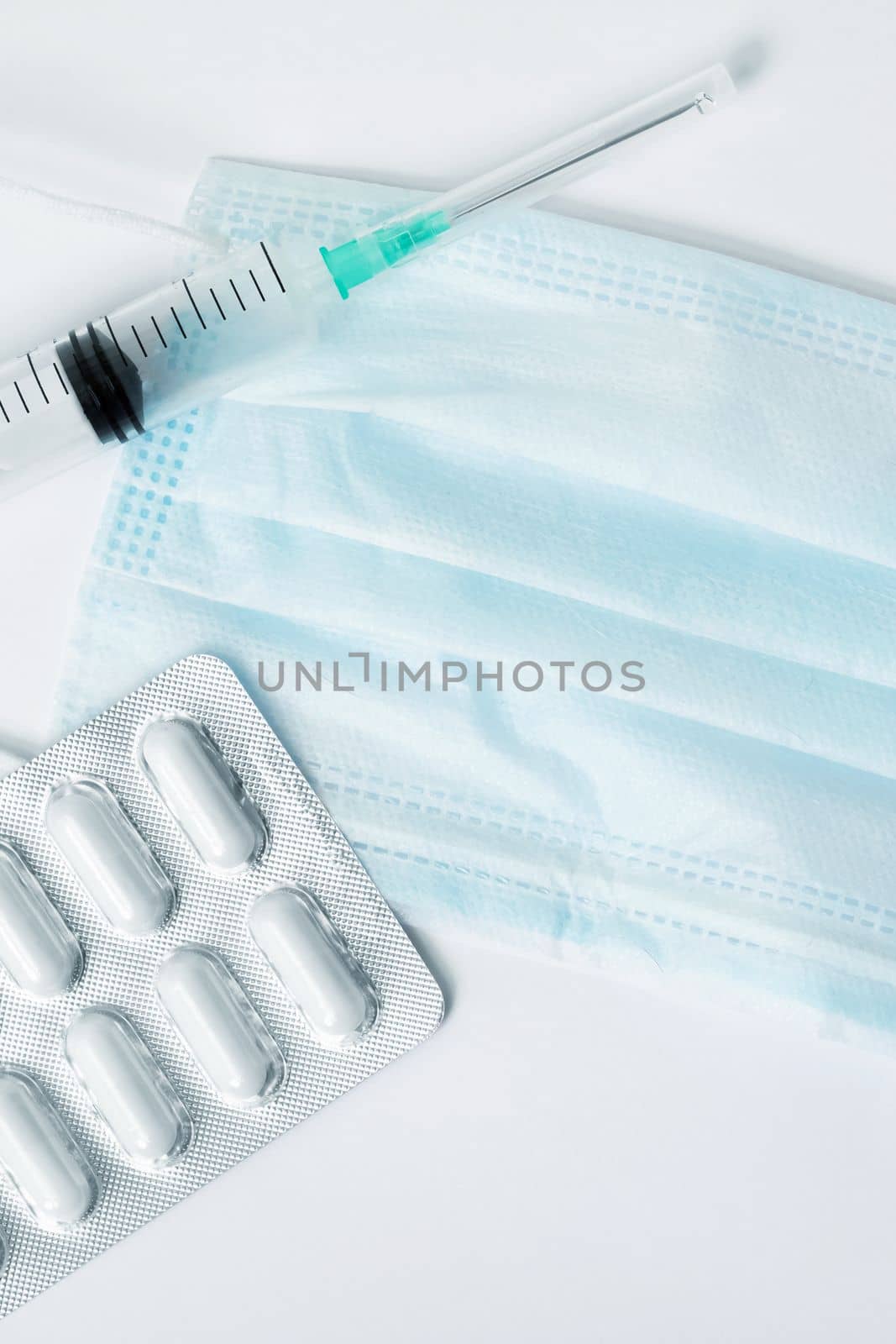 Protective medical mask, syringe, stethoscope and pills on a white background, copy space