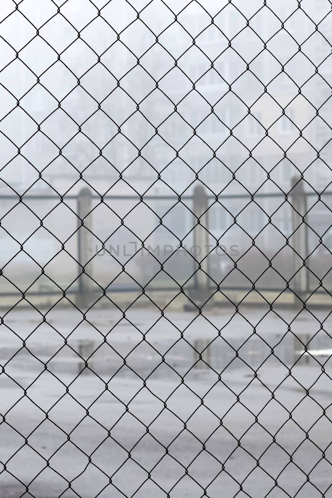Fence net against the backdrop of a playground for games in the fog